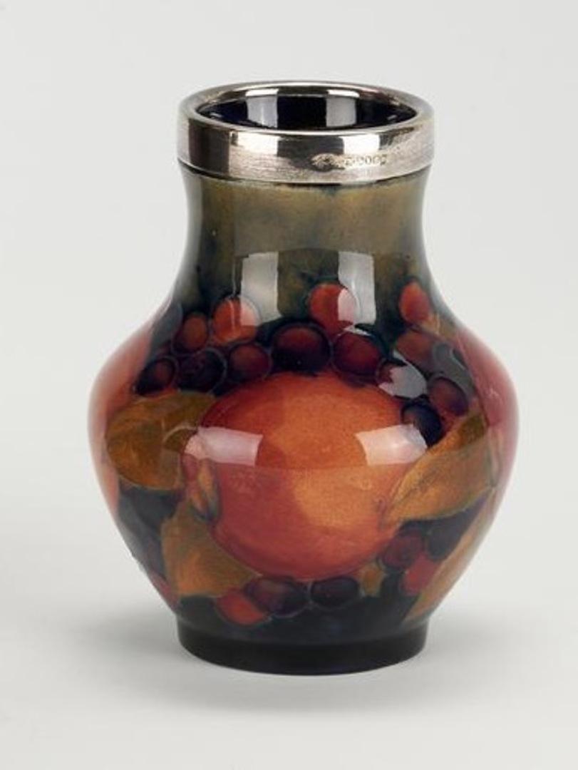 MOORCROFT Art Pottery POMEGRANATE small vase with silver plated rim. Circa 1930.

Highly collectable William Moorcroft pomegranate pattern small vase with silver plated rim, stamped with 