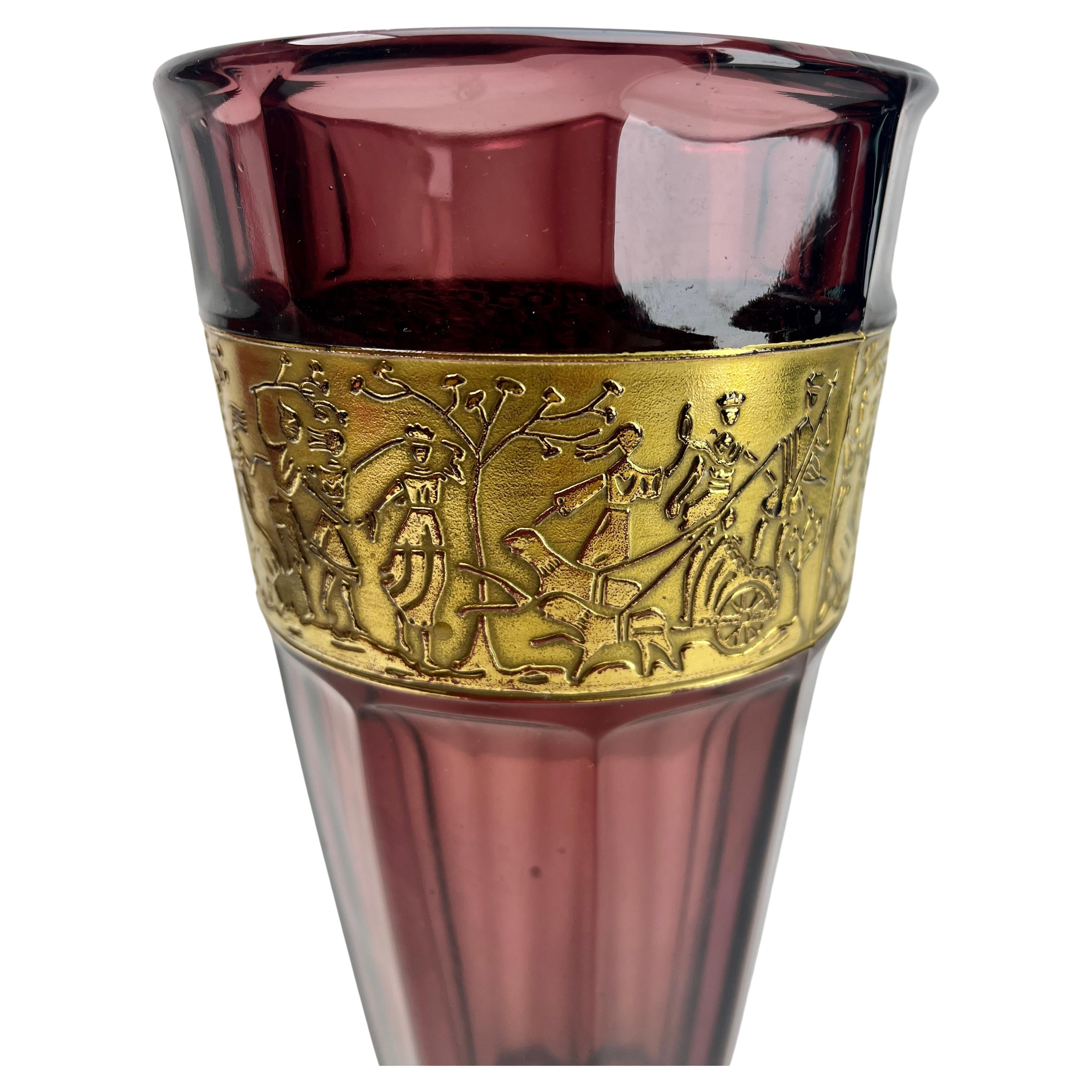 Vase aus geätztem Braunglas von Leo Moser aus der Zeit des Art déco.
Der sich verbreiternde Rand liegt über einer vergoldeten Relieftafel, die Amazonenkriegerinnen über einem facettenreichen Körper darstellt.
Moser, Karlsbad, hergestellt in der