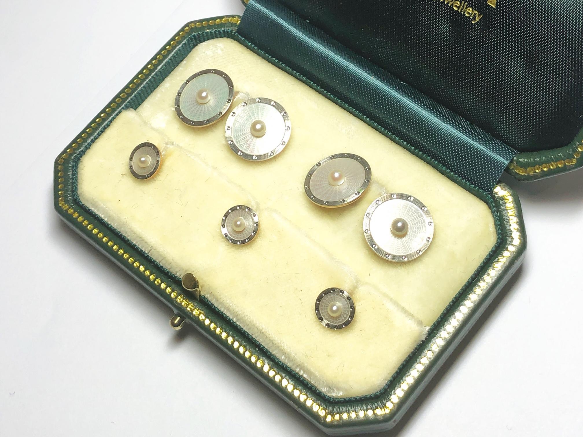 A French Art Deco mother-of-pearl dress-set, mounted in gold, with natural central seed pearls, on mother-of-pearl, with surrounding white enamel, in a Lamarche Guy Fils box, with bar fittings.