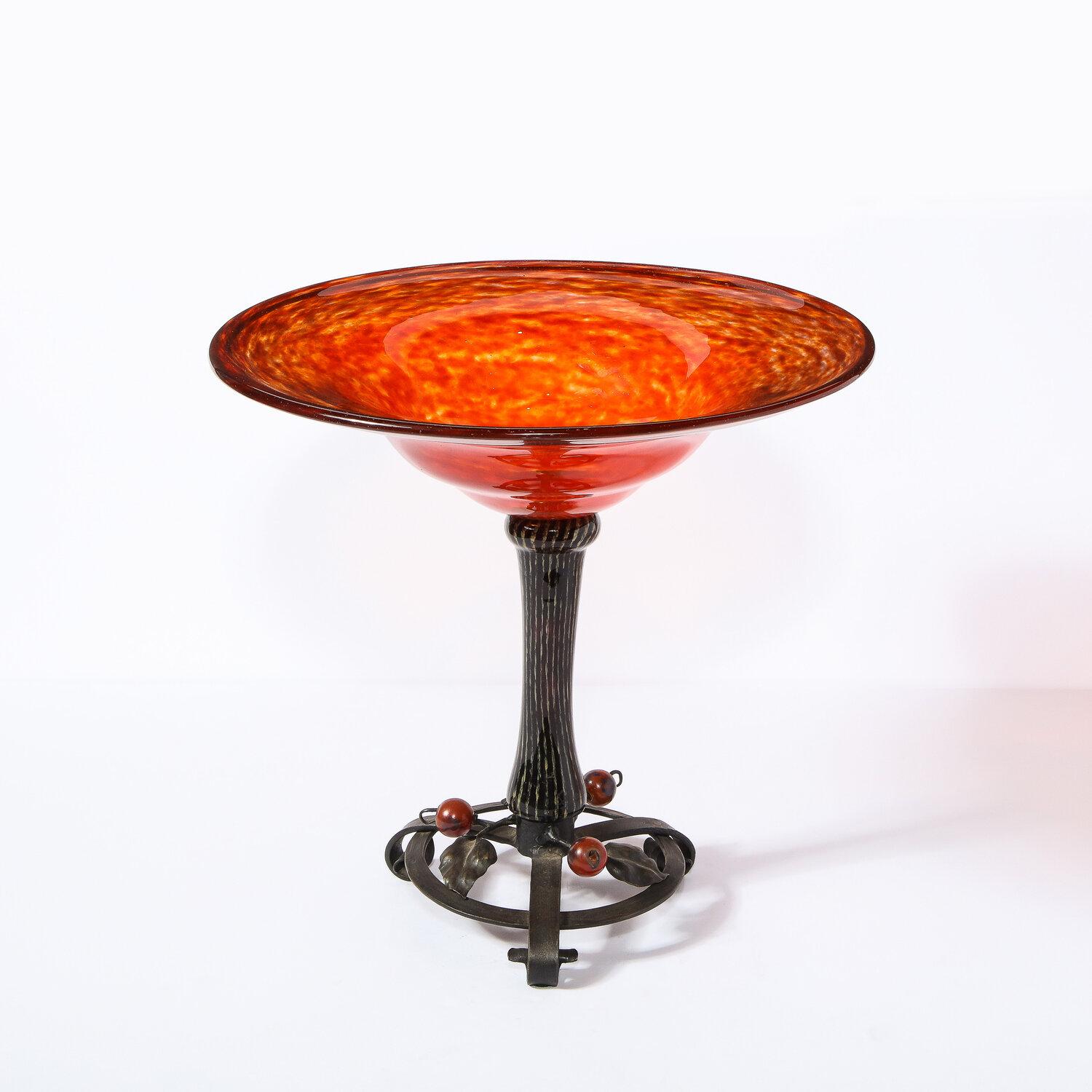 Ce bol sophistiqué de style Art déco a été réalisé et signé par Charles Schneider en France vers 1920. Elle présente un plateau en verre tacheté de cornaline et une base en fer forgé ornée d'ornements sphériques rubis et de détails feuillagés