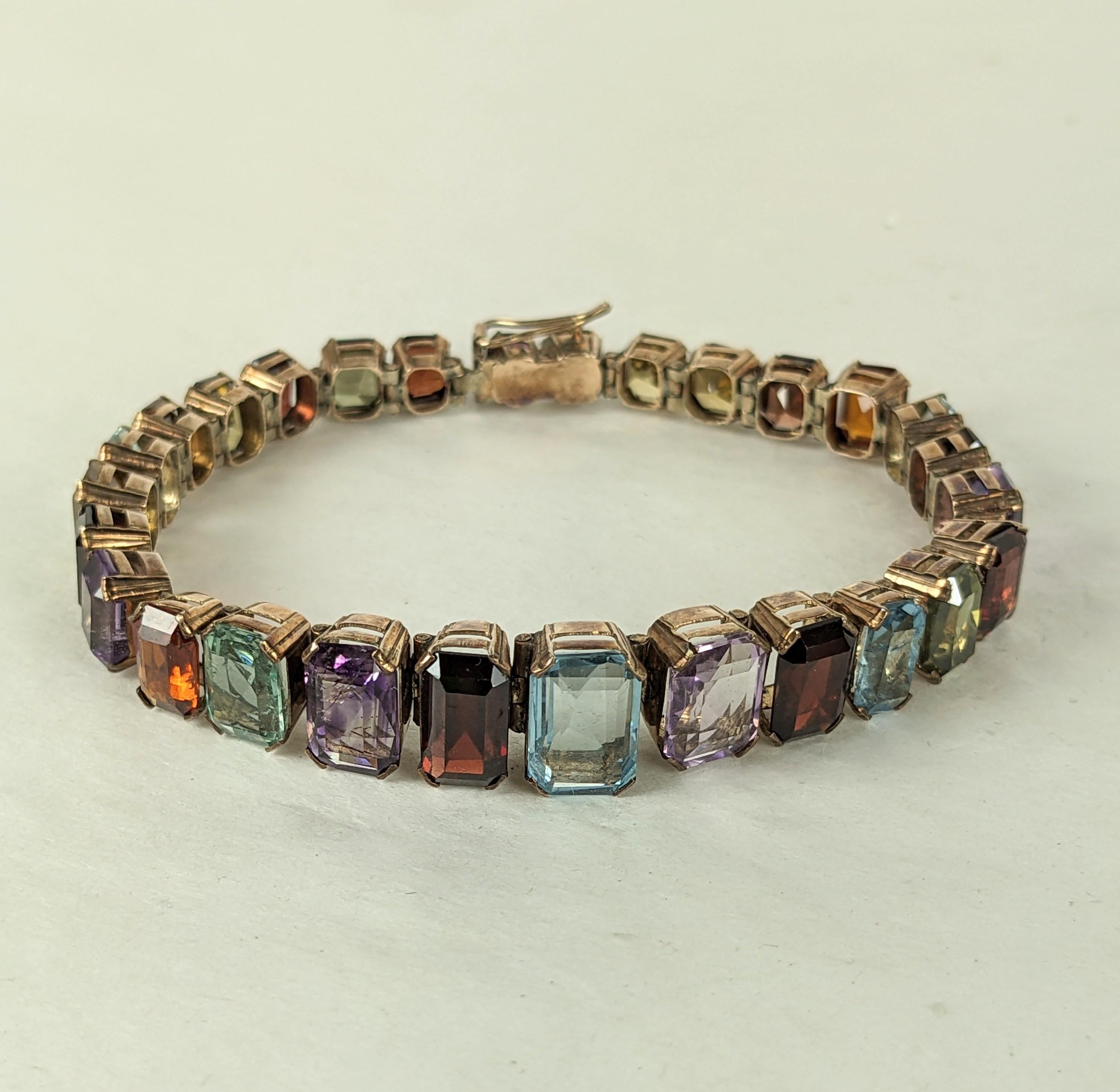 Attractive and Unusual Art Deco Multi Gem Line Bracelet in sterling vermeil from the 1940's. Unusual bracelet with rectangular, graduated gemstones with slight tonal variations and cuts, each in its own articulated setting. Lovely array of colored
