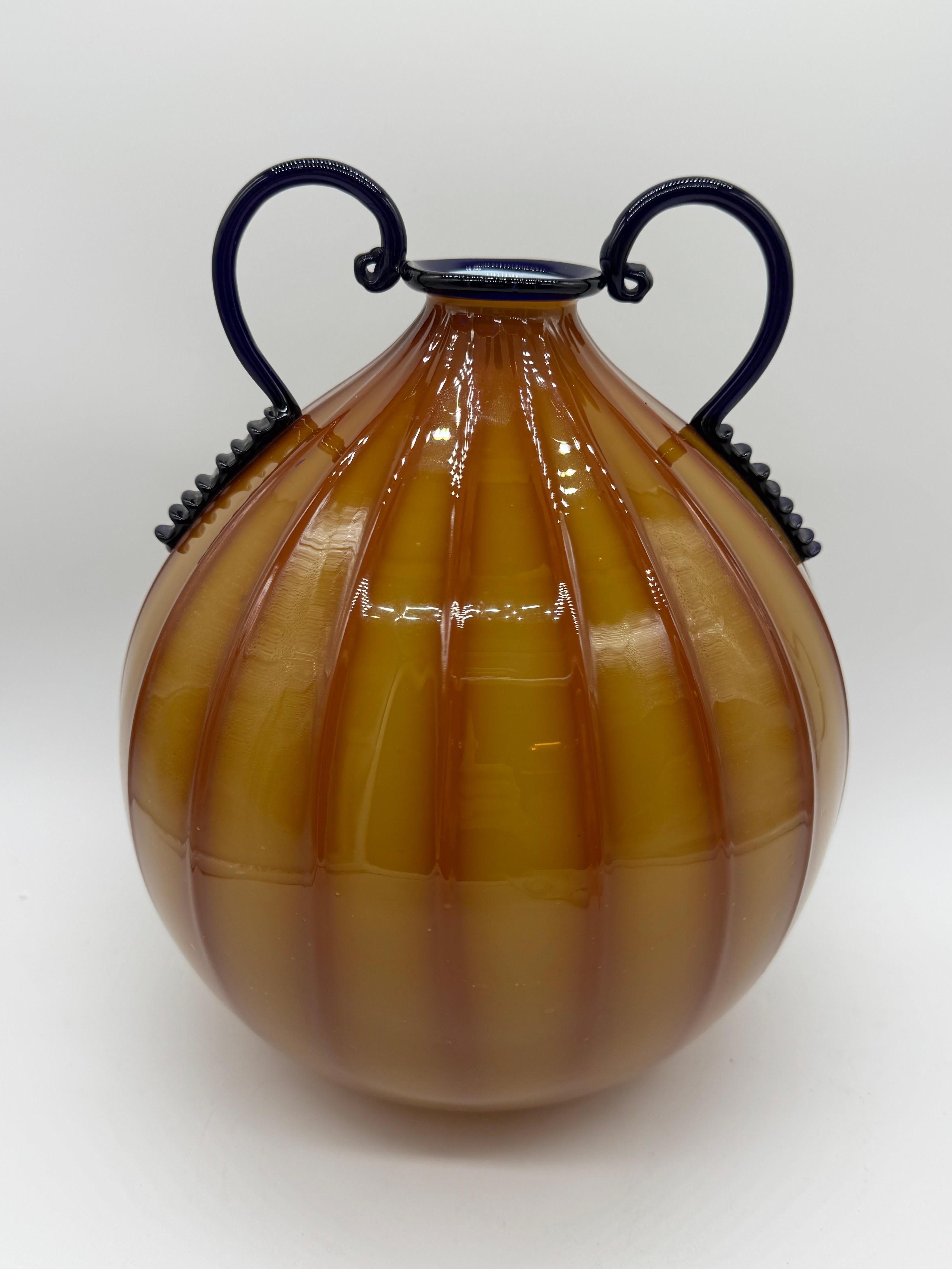 Immerse yourself in the timeless elegance of Art Deco with this exquisite Murano glass amphora, a masterful creation by the prestigious Fratelli Toso house. This piece is not only a testament to beauty, but also to the technique and tradition that