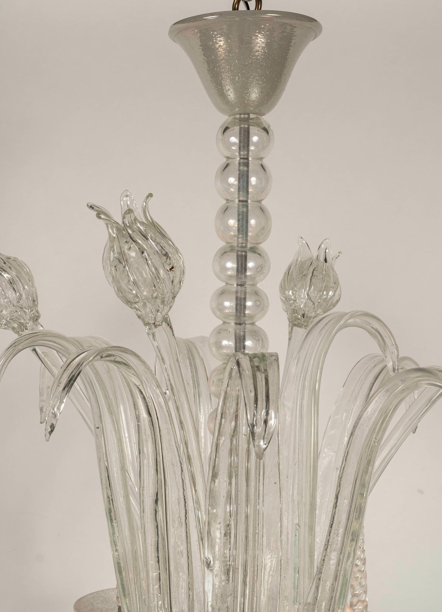 Un bellissimo esemplare dell'inizio del XX secolo  Lampadario a tulipano in vetro di Murano Art Déco composto da vetro trasparente e opalino soffiato a mano.  Questo lampadario ha 8 bracci e presenta tulipani in vetro e fogliame.