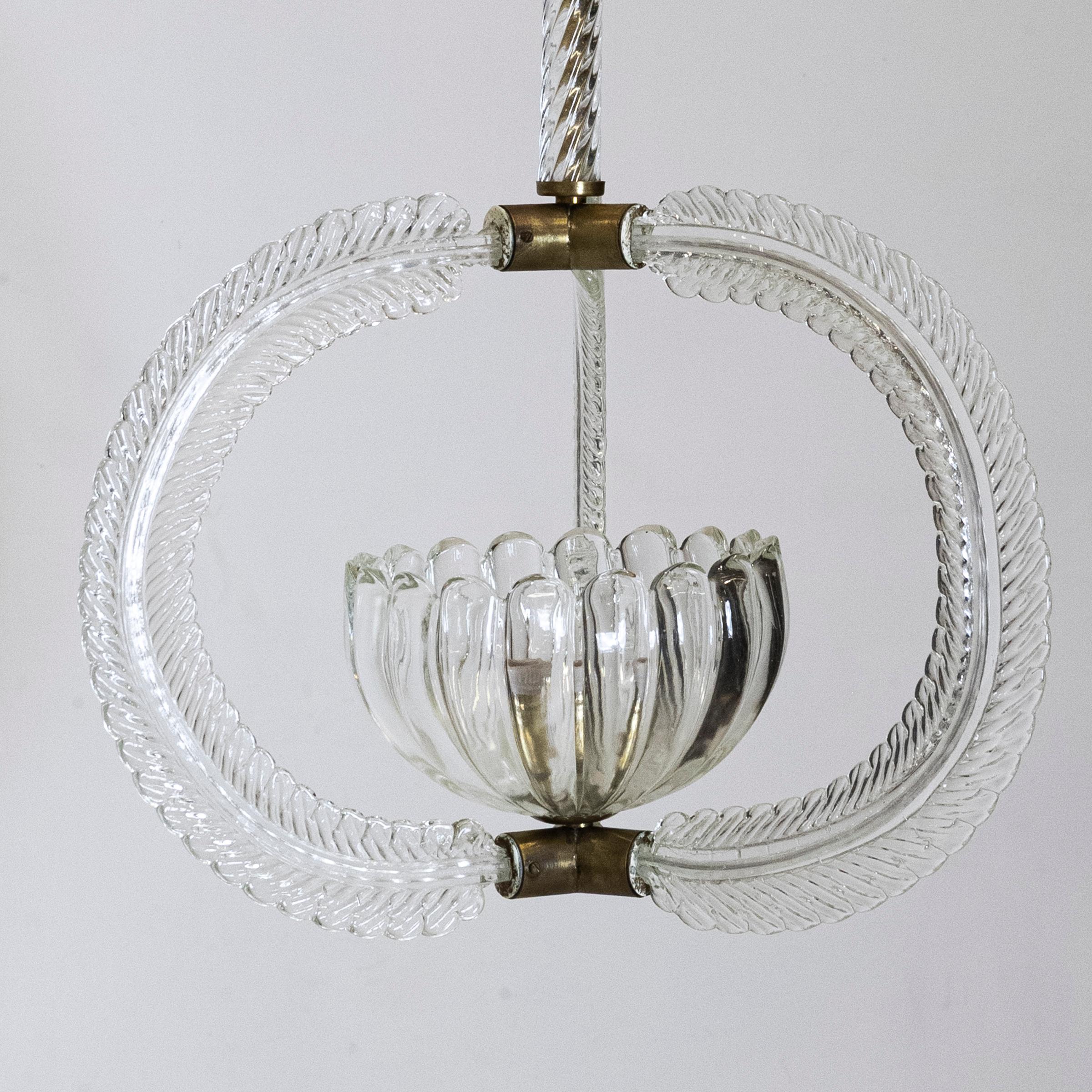Graceful Murano chandelier by Ercole Barovier. c. 1930s
The long brass stem suspends from a fluted rose and is encased in Murano glass. The pretty bowl light rests in an orb of 3 pieces of finely formed glass arcs. A very delicate and pretty piece
