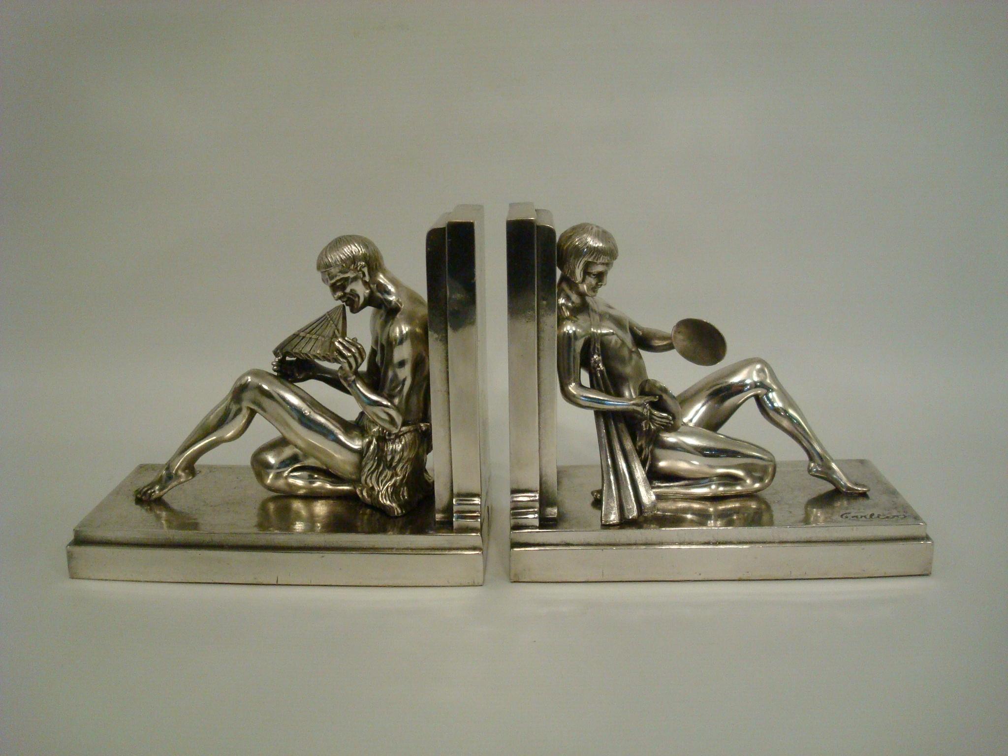 Serre-livres Art déco d'Emile Joseph Nestor Carlier, français, vers 1925, moulés en métal argenté représentant un homme vêtu d'un pagne jouant de la flûte de Pan et une femme vêtue de la même manière jouant des cymbales, recouverts d'un placage