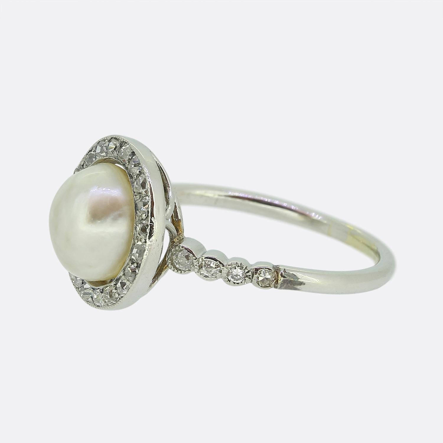 Ecco uno splendido anello a grappolo realizzato in un'epoca in cui lo stile Art Déco era all'apice del design mondiale. Una singola perla naturale di forma rotonda si trova al centro del viso in un'incastonatura aperta sul retro. Questa pietra