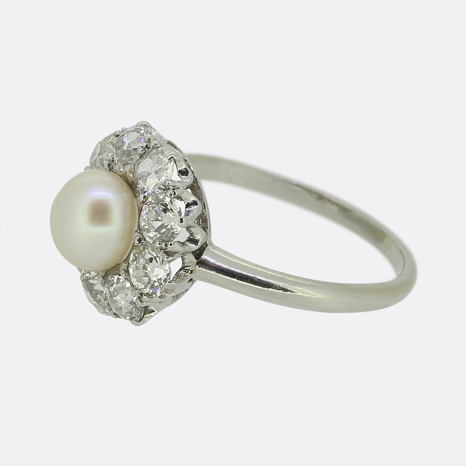 Nous avons ici une magnifique bague à perles et à diamants datant du début du 20e siècle. Une perle blanche ronde naturelle d'un bel éclat se trouve au centre de la face et est entourée de gros diamants de taille ancienne bien assortis. La bague a