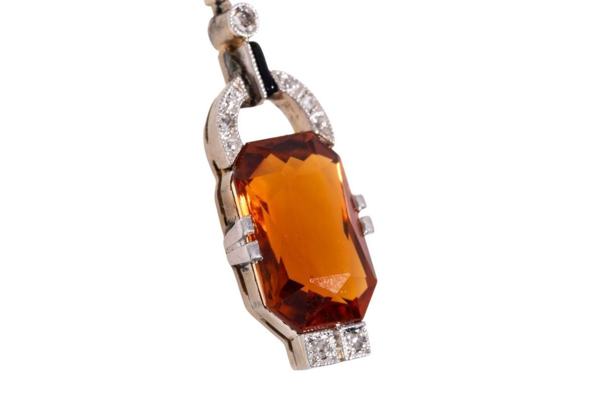 Una delicata collana Art Deco con un citrino ottagonale sfaccettato di colore arancione intenso. Inoltre è decorato con diamanti taglio rosa e smalto nero, un elemento della linea di smalto è incompleto.

Collana in oro giallo 18 carati e platino
