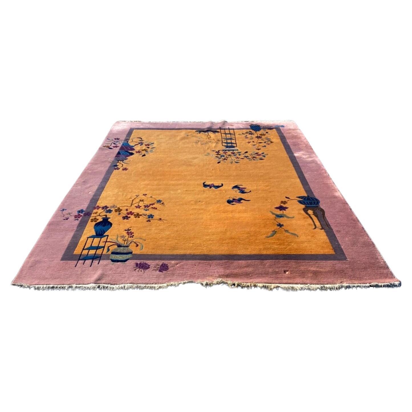 Antico tappeto cinese Art Deco, attribuito a Walter Nichols. Questo tappeto in lana, annodato a mano e grande quanto una stanza, presenta un campo e un bordo a blocchi di colore nei colori senape, prugna e lavanda. Sprazzi dettagliati di fiori,