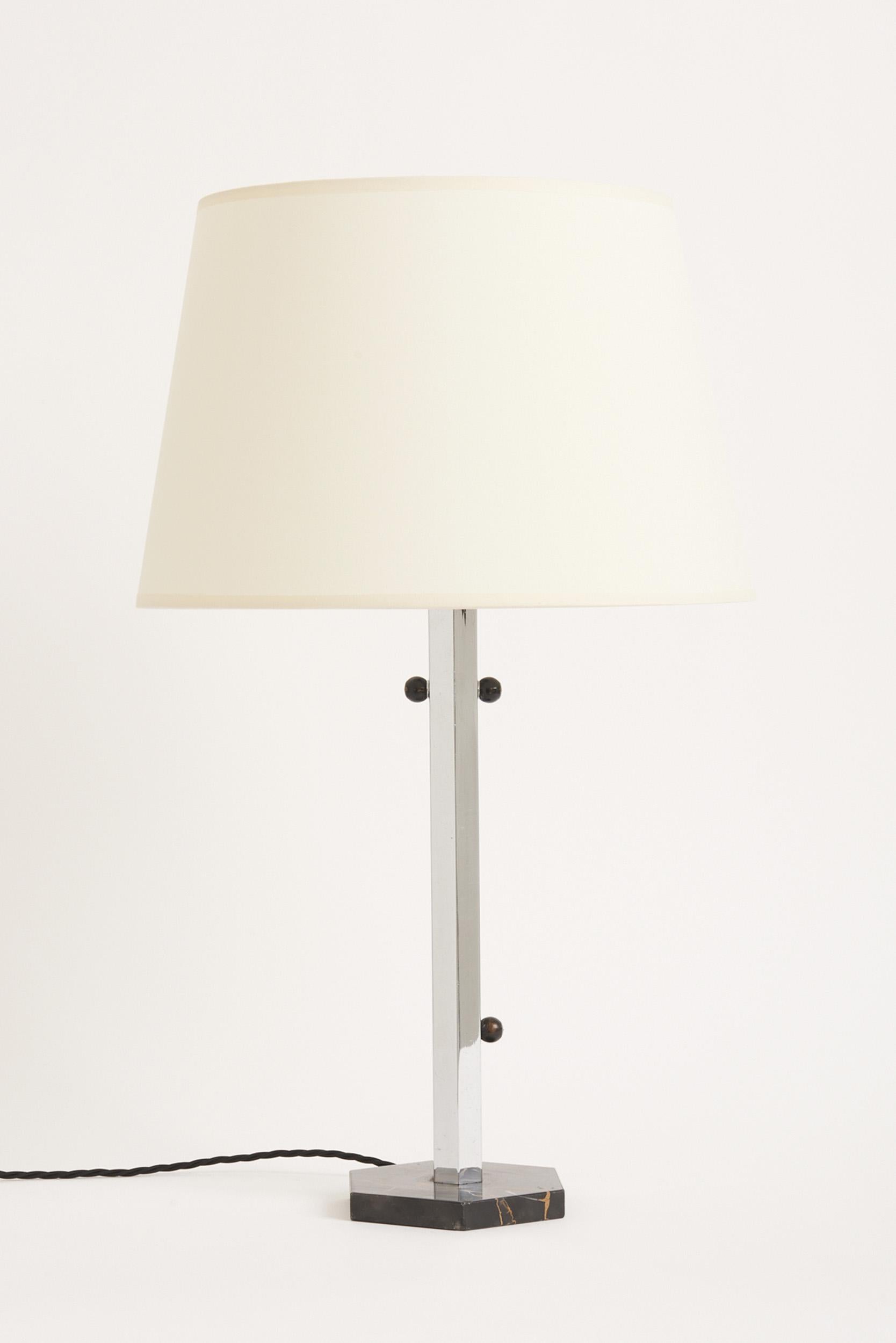 An Art Deco nickel and Portoro marble table lamp.
France, Circa 1930.
With the shade: 64 cm high by 36 cm diameter.
Lamp base only: 47 cm high by 16 cm diameter.