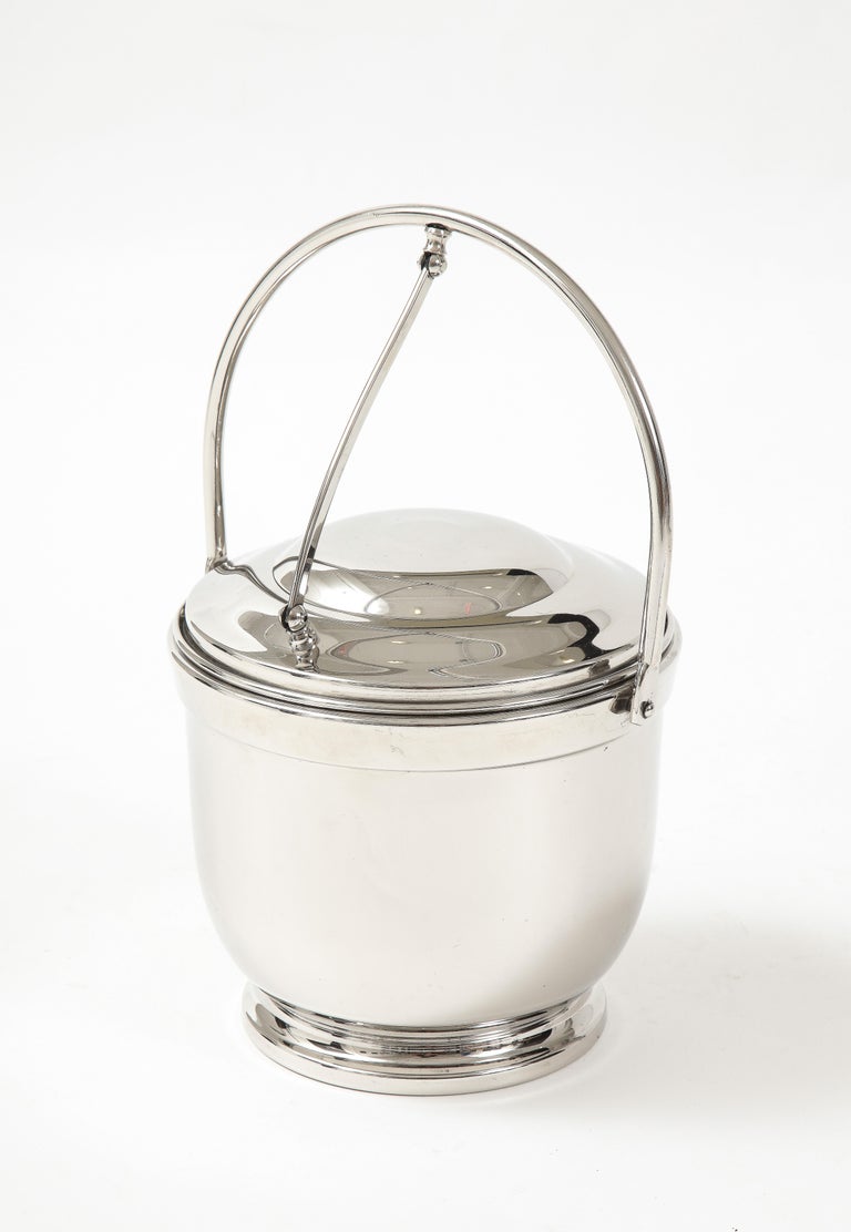 American Art Deco polished nickel ice bucket with attached lid and mercury glass liner. Ice container is 6.5 inches tall x 7.25 inches in diameter, with handle up the height is 12.25 inches.