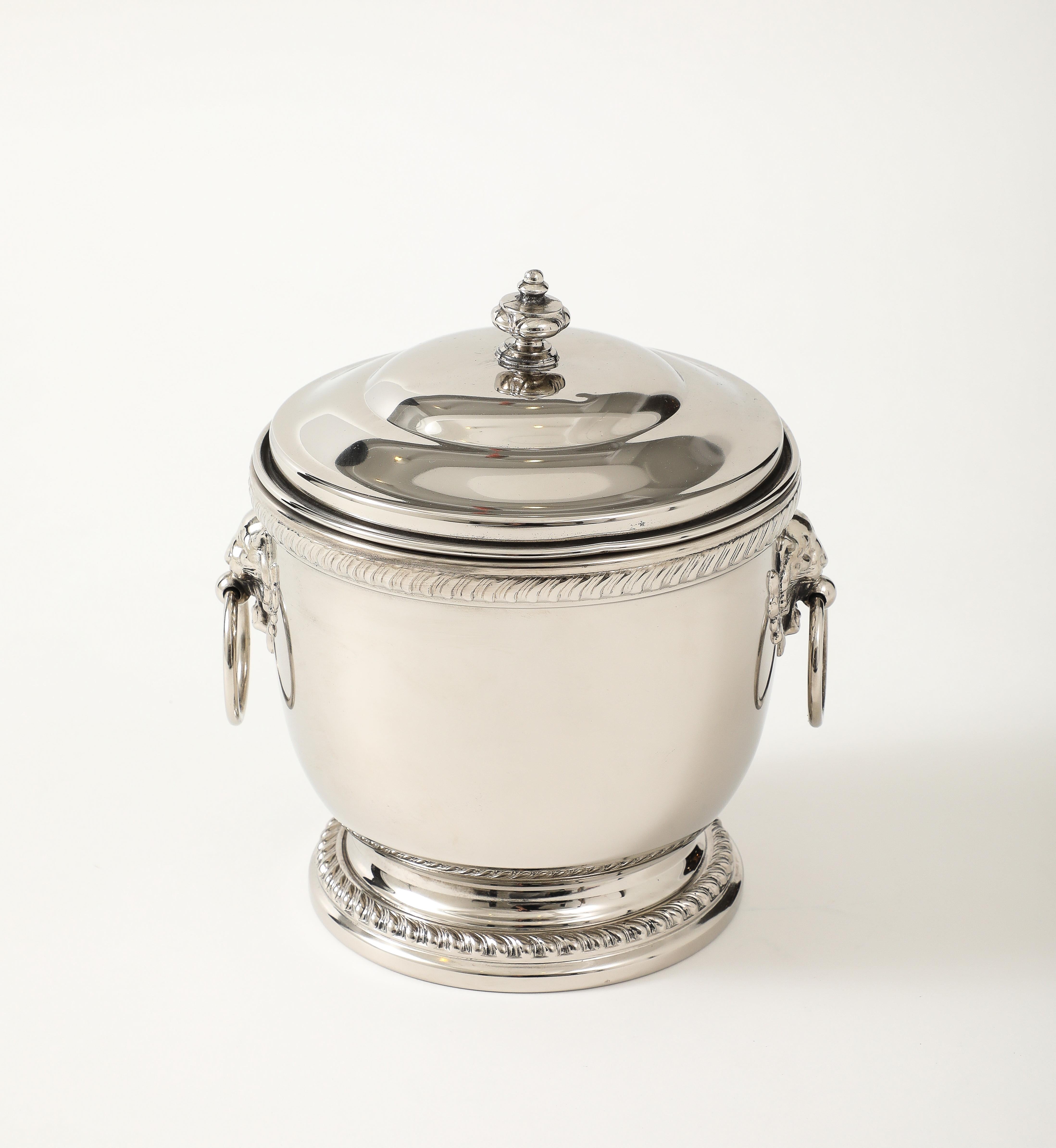 Art Deco polished nickel ice bucket with Mercury glass liner, lid and accented with stylized lion's head ring pulls.