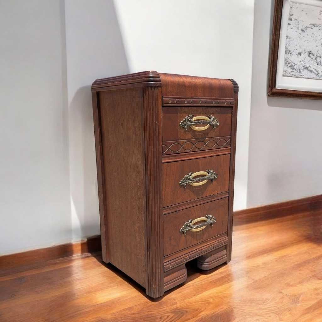Une table de nuit originale dans la tradition Art déco des années 1930, fabriquée en bois aux tons chauds et présentant des bords en cascade classiques et des courbes épurées. Cette pièce compacte mais élégante allie un design intemporel à une