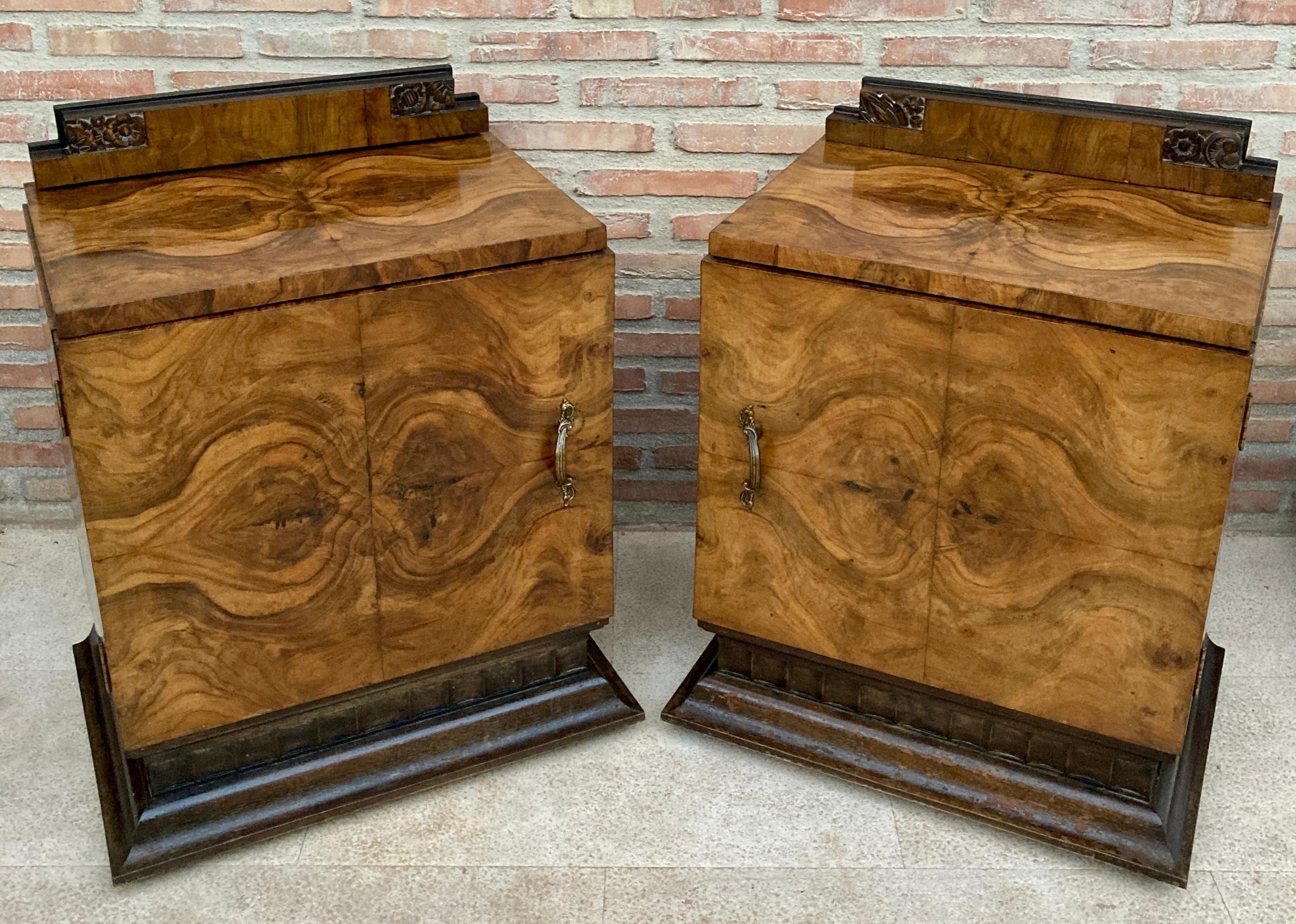 This pair of circa 1930s French art deco side cabinets could be used to flank a sofa or as nightstands. Each has a storage compartment with a hinged door and narrow open shelves on the sides and an interior drawer. The cabinets sit on an ebonized