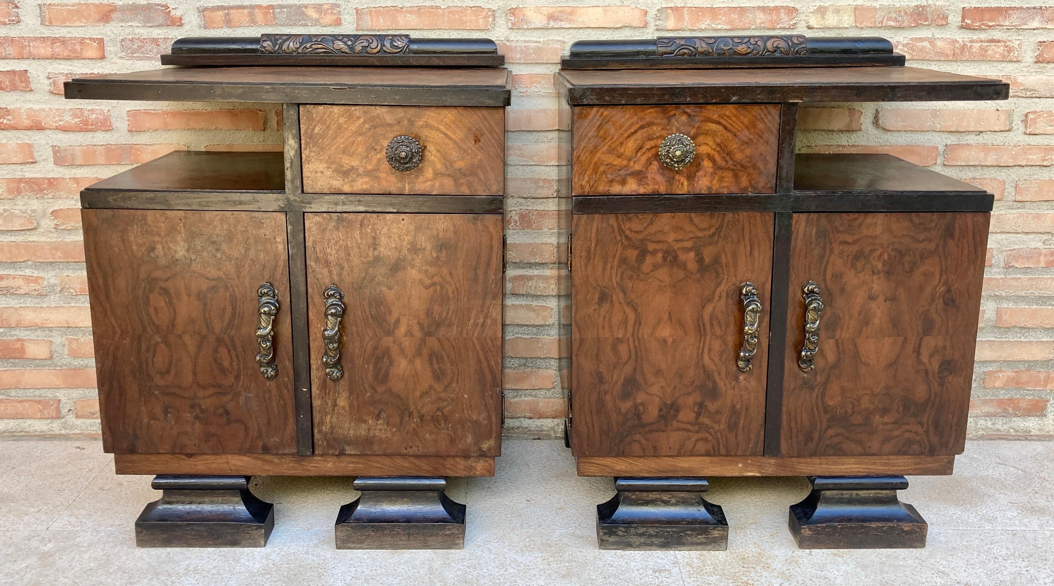 This pair of French Art Deco side cabinets from the circa 1930's could be used to flank a sofa or as nightstands. Each has two storage compartments with a hinged door and a narrow open shelf on one side and a small drawer on the other. The cabinets