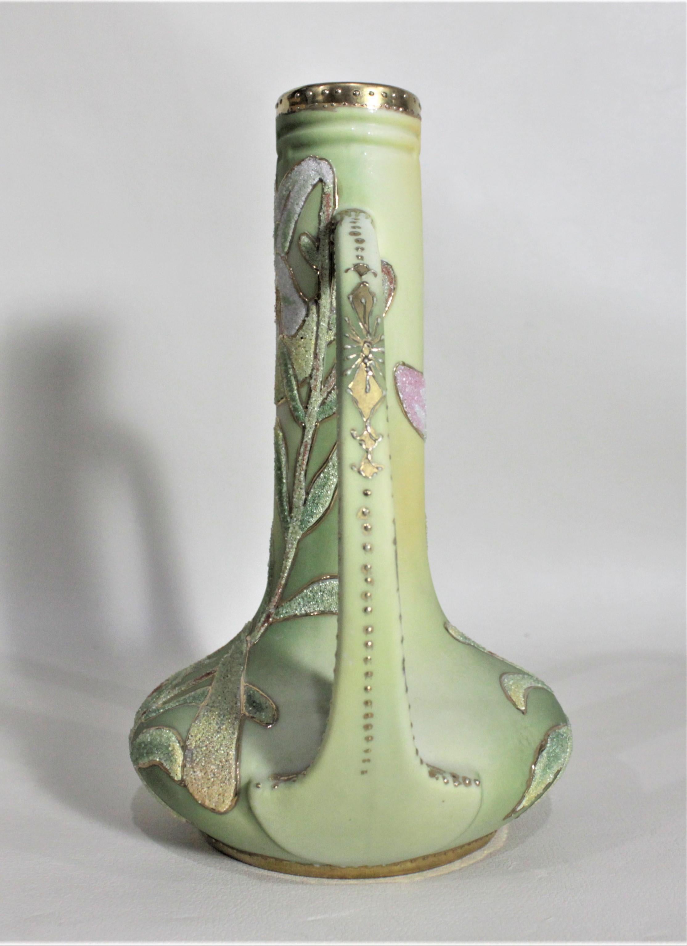 This hand painted porcelain floral vase was made by Nippon of Japan in circa 1920 in the Art Deco style. The vase is done in their signature Coralene pattern in a muted green tone with hand painted white flowers on both the front and back. The vase