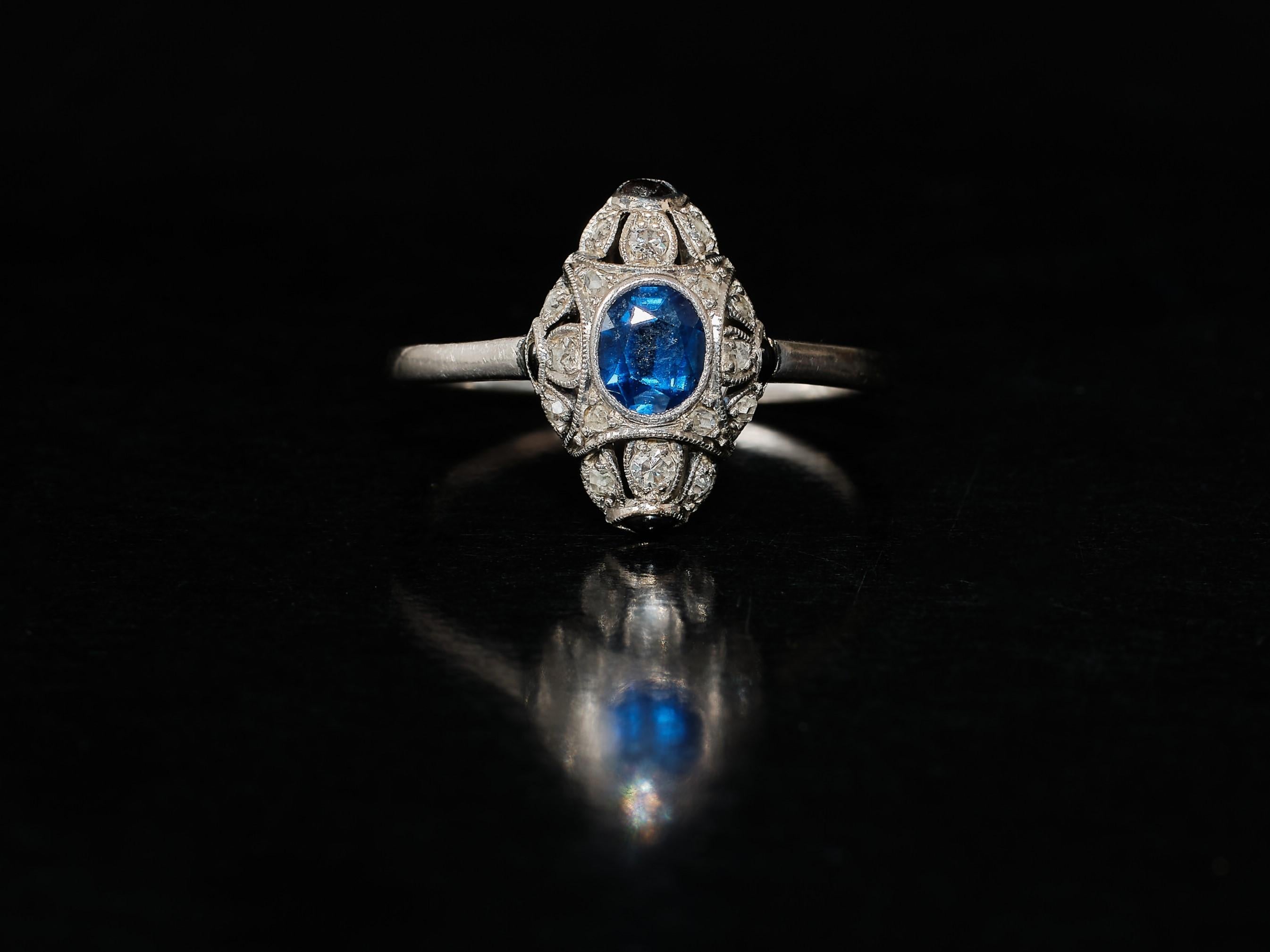 A very stylish antique sapphire ring from the Art Deco era. Small but oh so sweet. 1920s glamour! A lozenge shape frame centering a oval cut sapphire estimated to weigh approx. 0.39 ct. surrounded by 16 small diamonds, old and single cut.  The