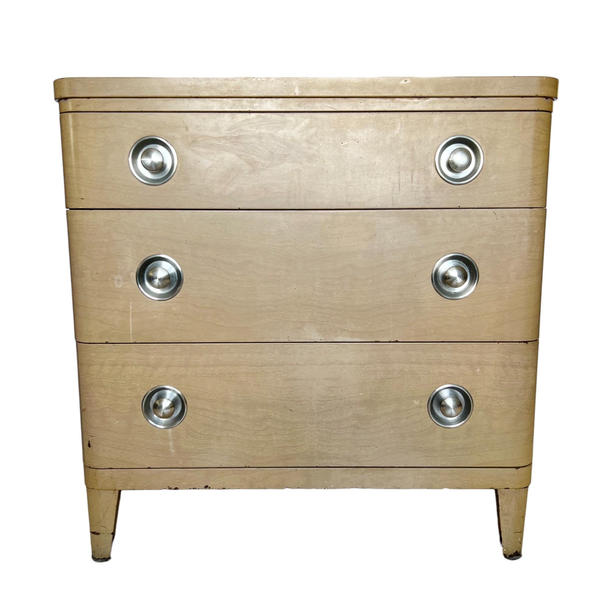 Eine industrielle Art-Deco-Metall-Kommode mit drei Schubladen und schwebendem Spiegel, entworfen von Norman Bel Geddes für Simmons Company Furniture um 1935. Faux-Bois-Emaille-Finish mit eingelassenen Griffen aus gebürstetem Edelstahl. Der