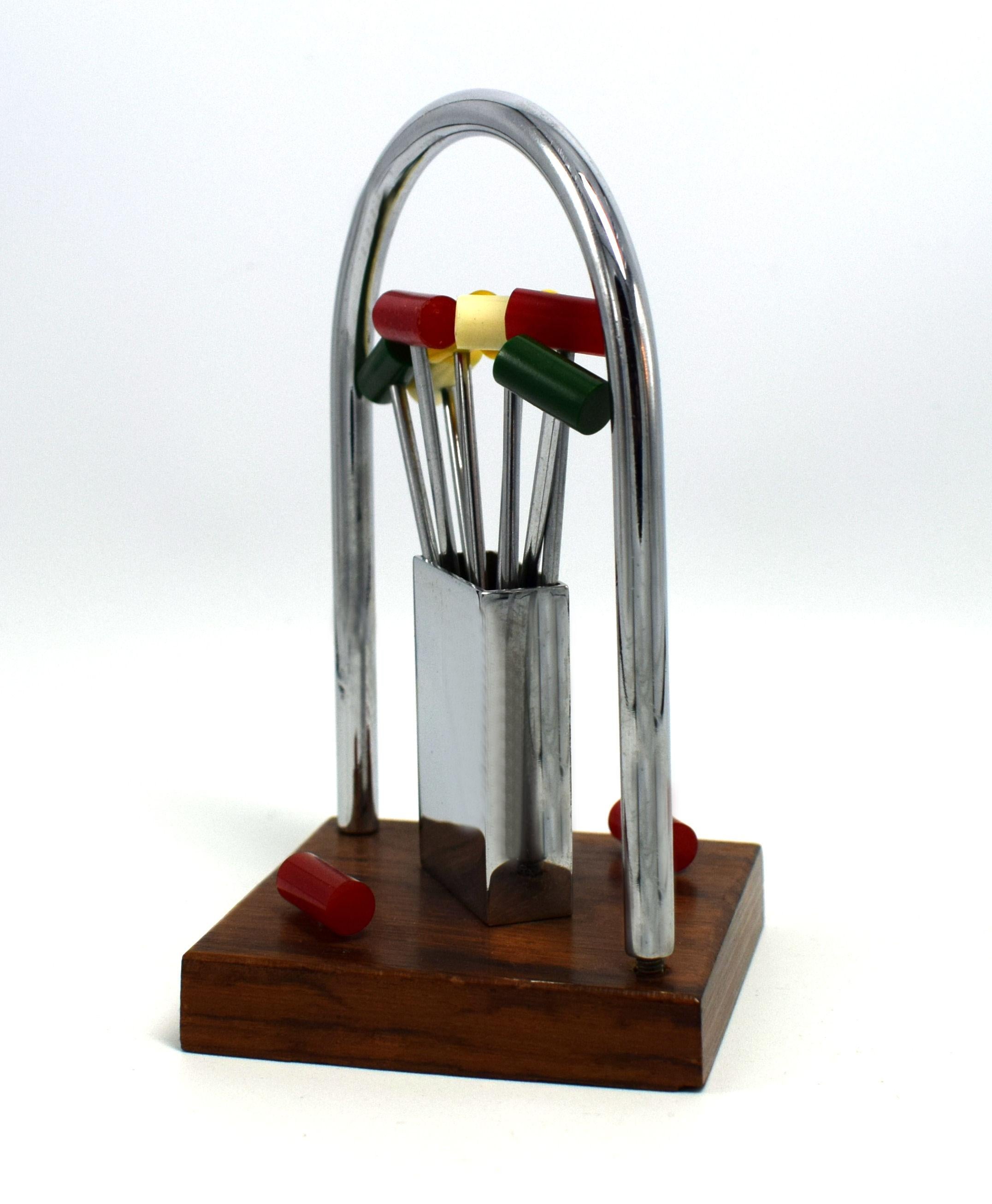 A novelty 1930s cocktail stick set in the manner of a croquet set made in France. Features different coloured Bakelite cocktail sticks with chromed metal prongs, all contained within a chrome box hold on a walnut base. Great set in very good