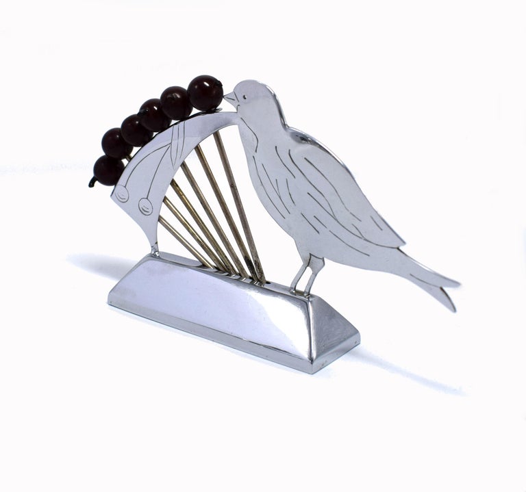 A charming novelty Art Deco 1930s cocktail stick set in the manner of a bird looking at a line up of six berries on a branch leaf. Made in France. Deep red colored phenolic bakelite berries with chromed metal prongs, all supported on a chrome