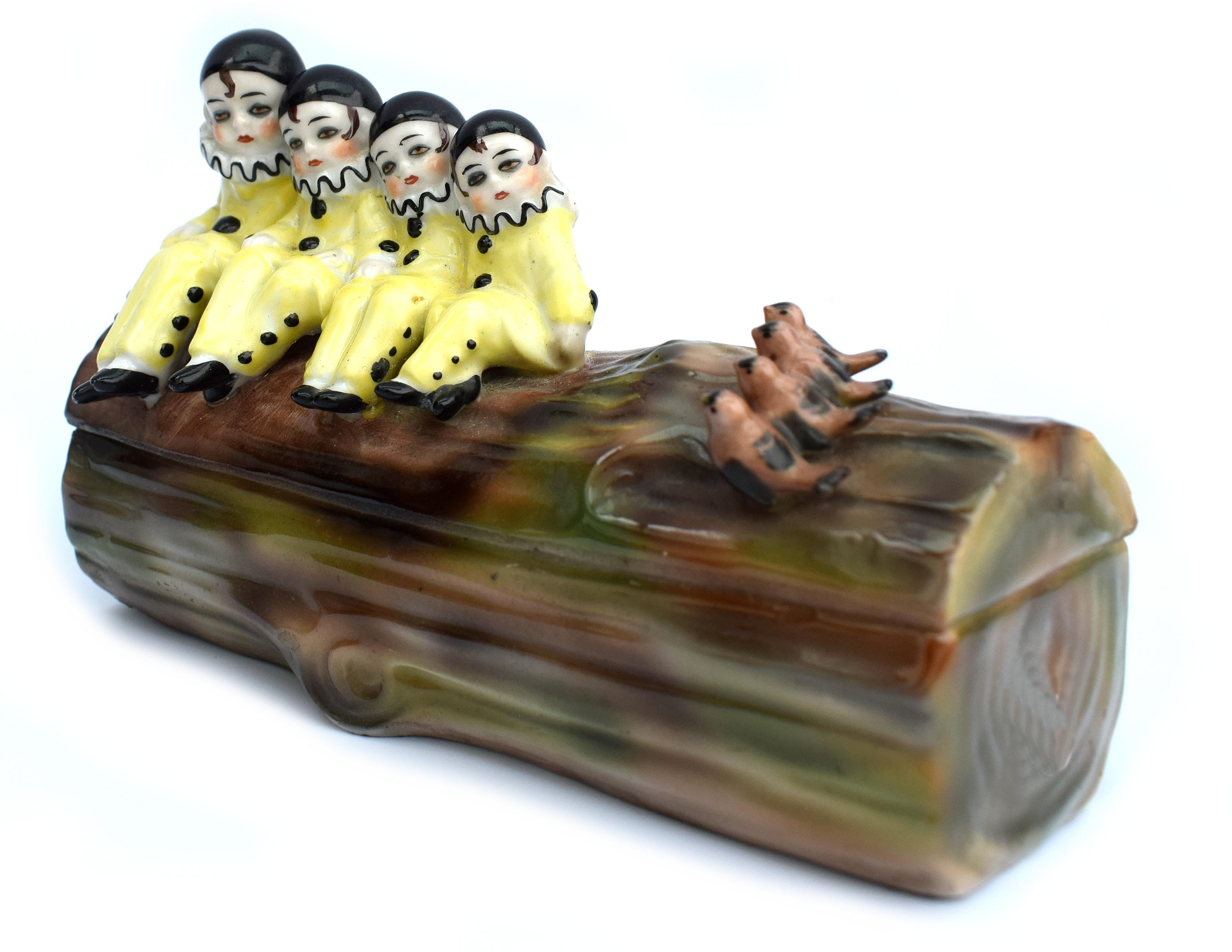 This really is a delightful piece and one we've not come across before. This is a 1930s Art Deco Novelty Pierrot Ceramic German Trinket Box, part of the half doll family. Features four child Pierrots sat on one end of a tree log with four small
