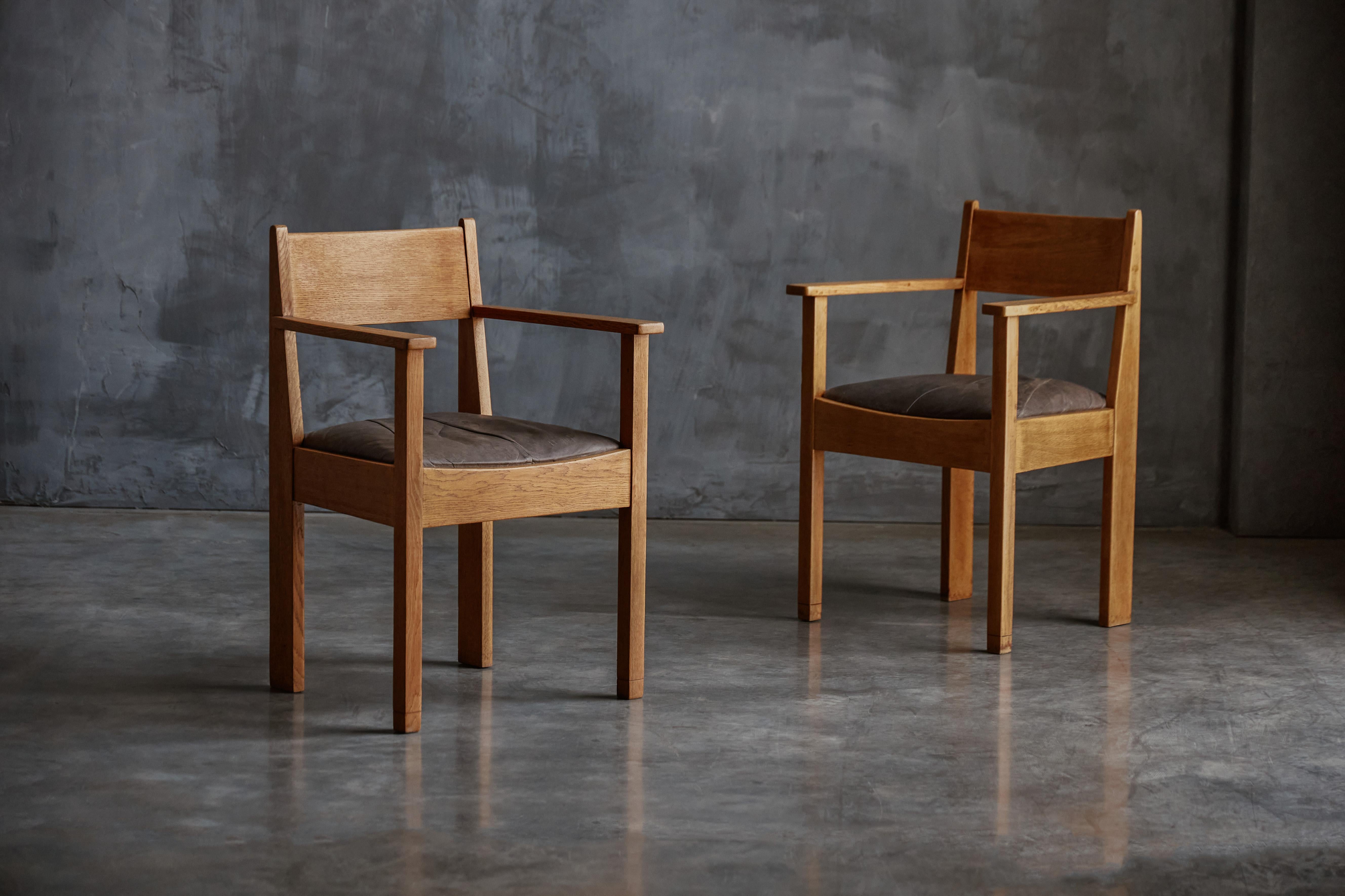 Fauteuils Art déco des années 1930 fabriqués en chêne riche avec une patine naturelle et chaleureuse. Ils présentent des lignes robustes et anguleuses qui reflètent la géométrie distincte du design Art déco. Les sièges sont recouverts de cuir,