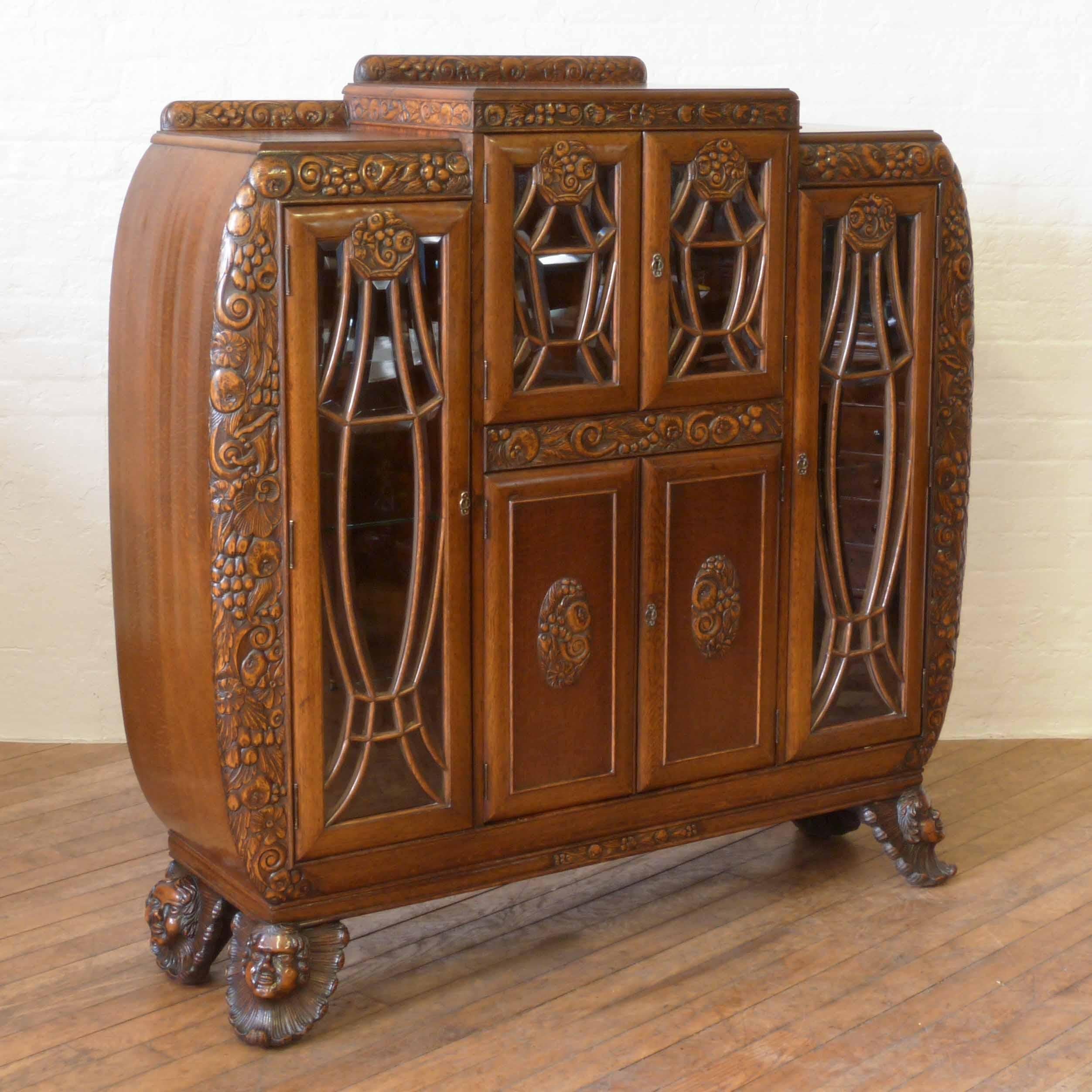 This is an exceptionally rare oak Art Deco cabinet with an extravaganza of decoration. From the foliate fruiting carved throughout to the precision bevelled glass all individually cut to each Art Deco inspired astragal door. The typical bowed sides