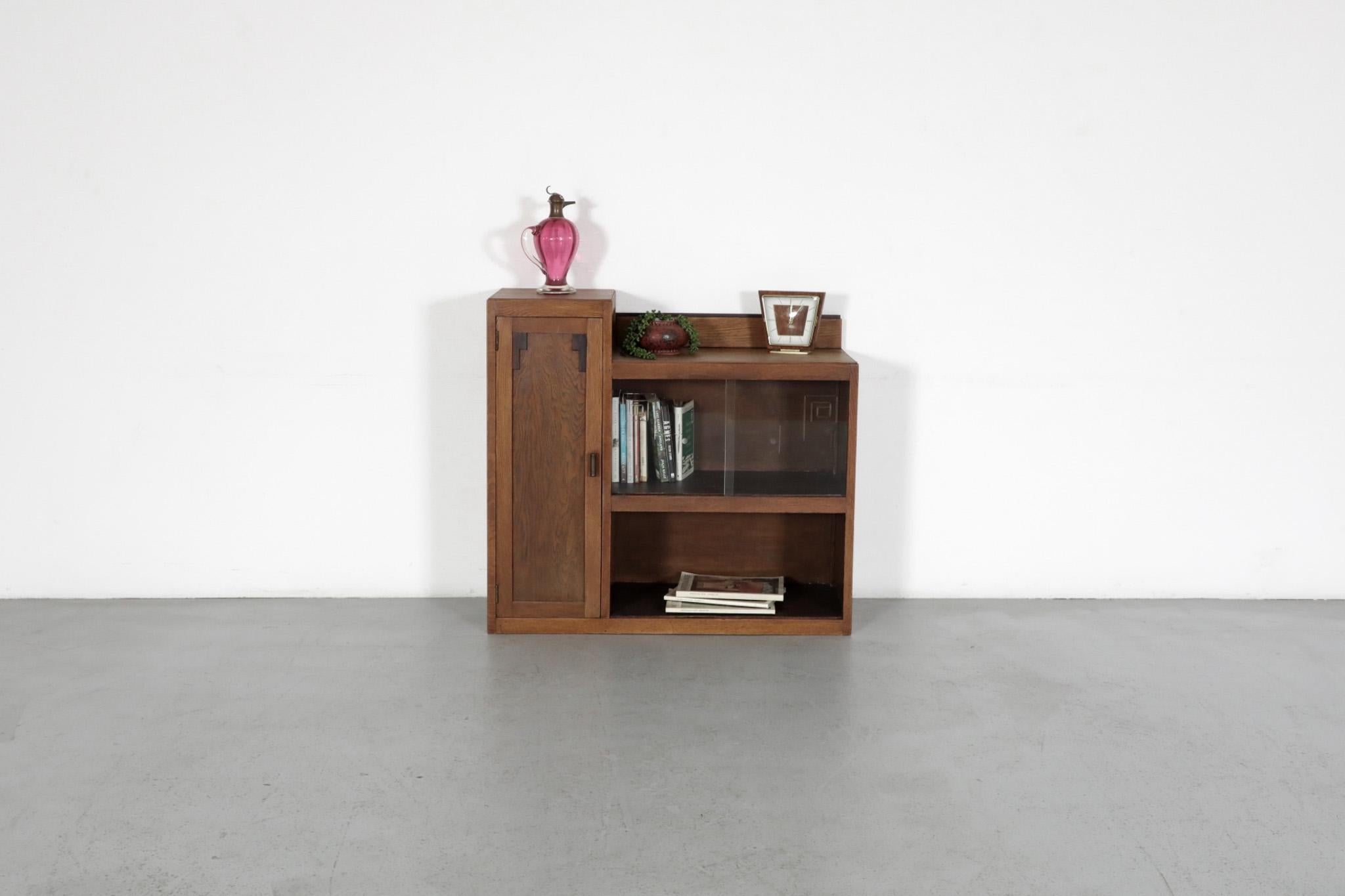 Amsterdam School oak cabinet with cocobolo accents, etched glass doors and an attached side cabinet with brass pull, and faux wood shelves. One glass door has a small chip on bottom edge, not very noticeable. In original condition with visible wear