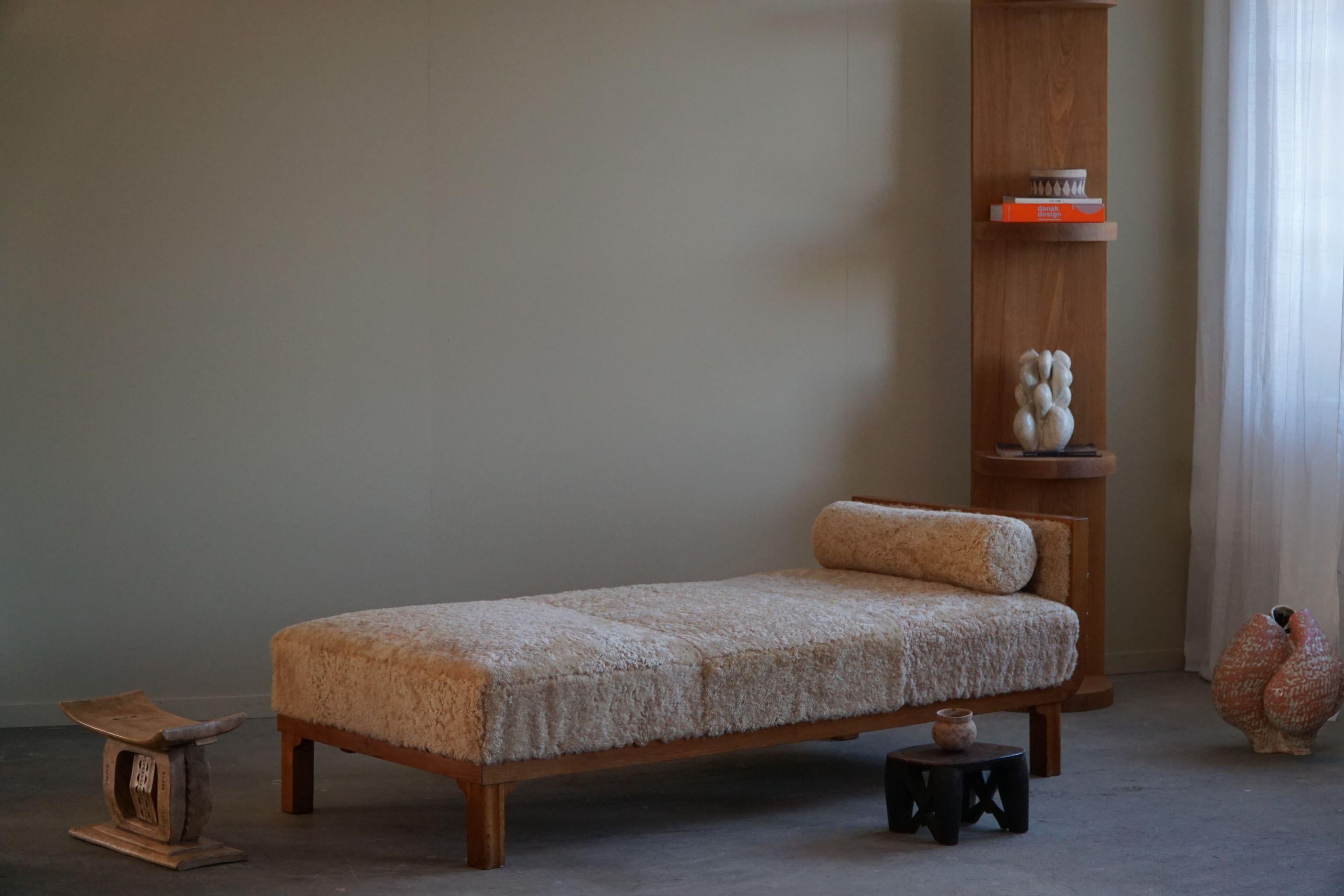 Immerse yourself in the elegance of mid-century design with this Art Deco daybed, expertly reupholstered in great quality lambswool. Crafted in the 1940s by a skilled Danish cabinetmaker, its oak frame boasts the clean lines characteristic of the