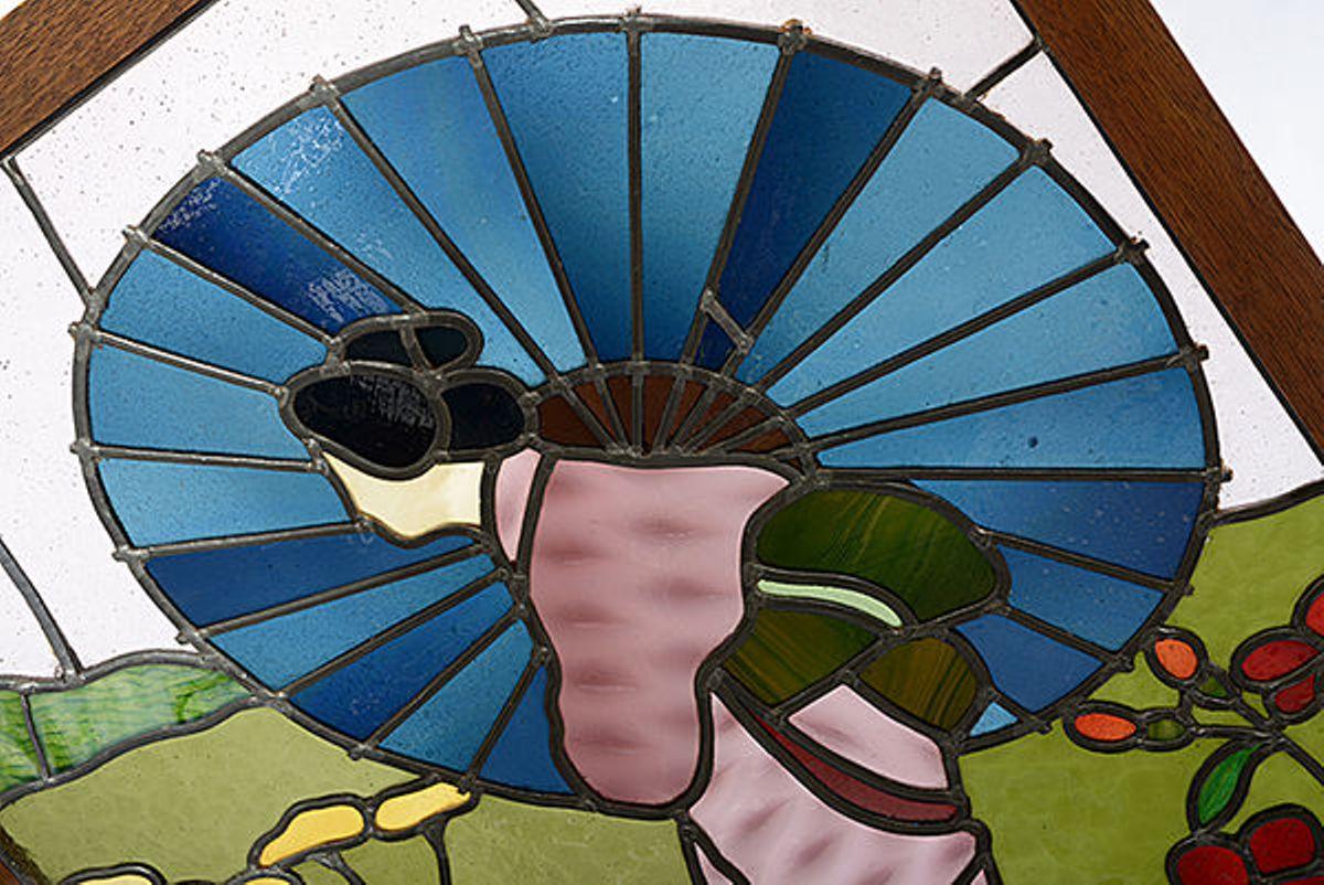 An oak framed Art Deco screen with a stained glass inset depicting a Japanese figure in a pink kimono holding a blue parasol standing in a garden of flowers.
The oak frame with a brass ring pull handle to each side, is raised on tressel feet.
 
