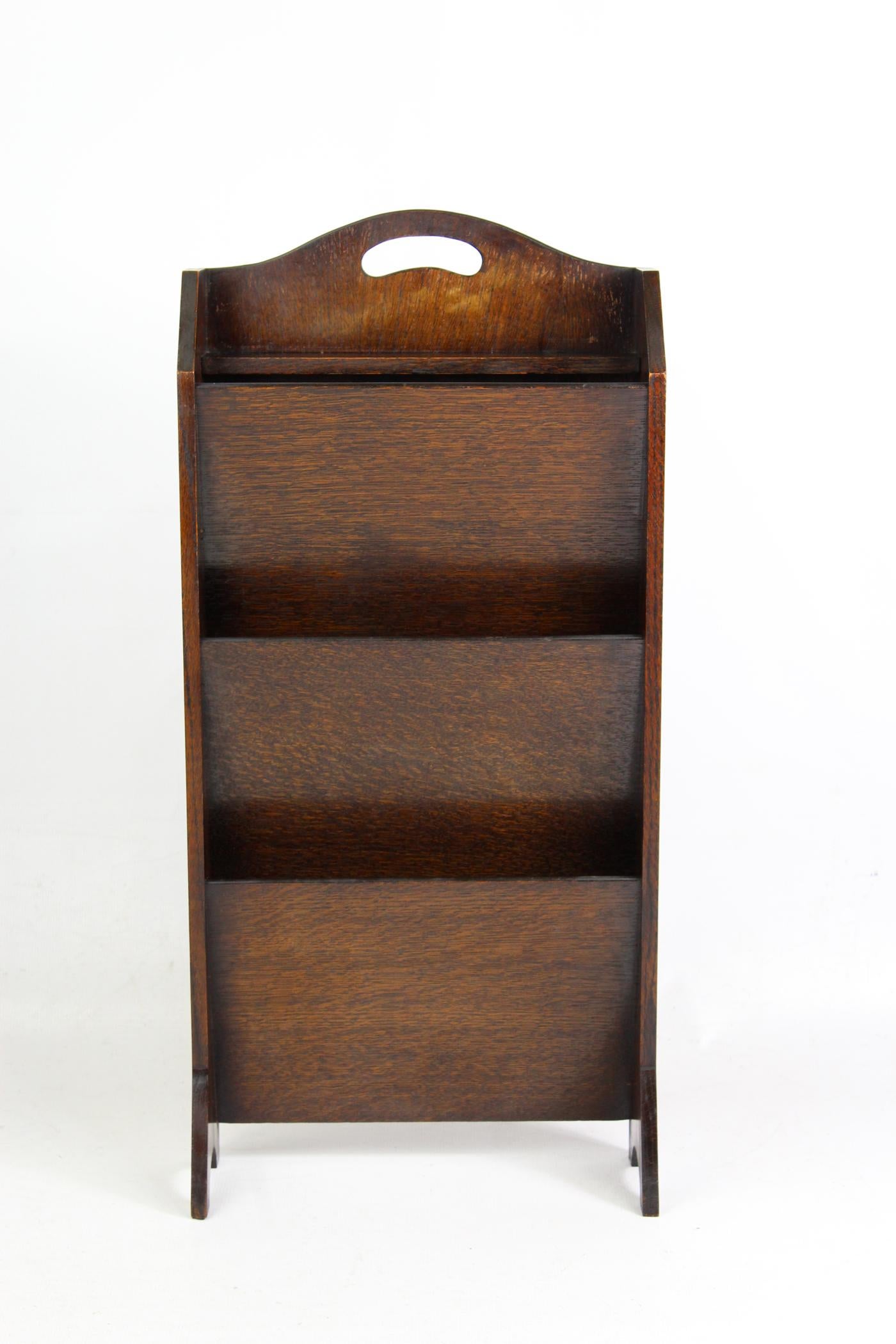 A charming small Art Deco oak newspaper or magazine stand dating from circa 1920s. With 3 angled book shelves for holding magazines or newspapers and a small shelf to the top. It has canted sides and a pierced carry handle to the top and stands on