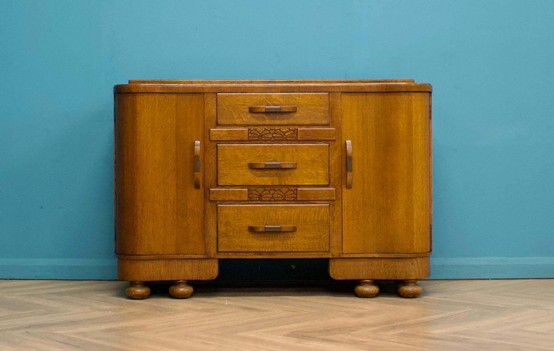 This high-quality goldon oak Art Deco sideboard, circa 1930s.
Featuring two cupboards, each with shelves.
There are also three drawers to the middle.