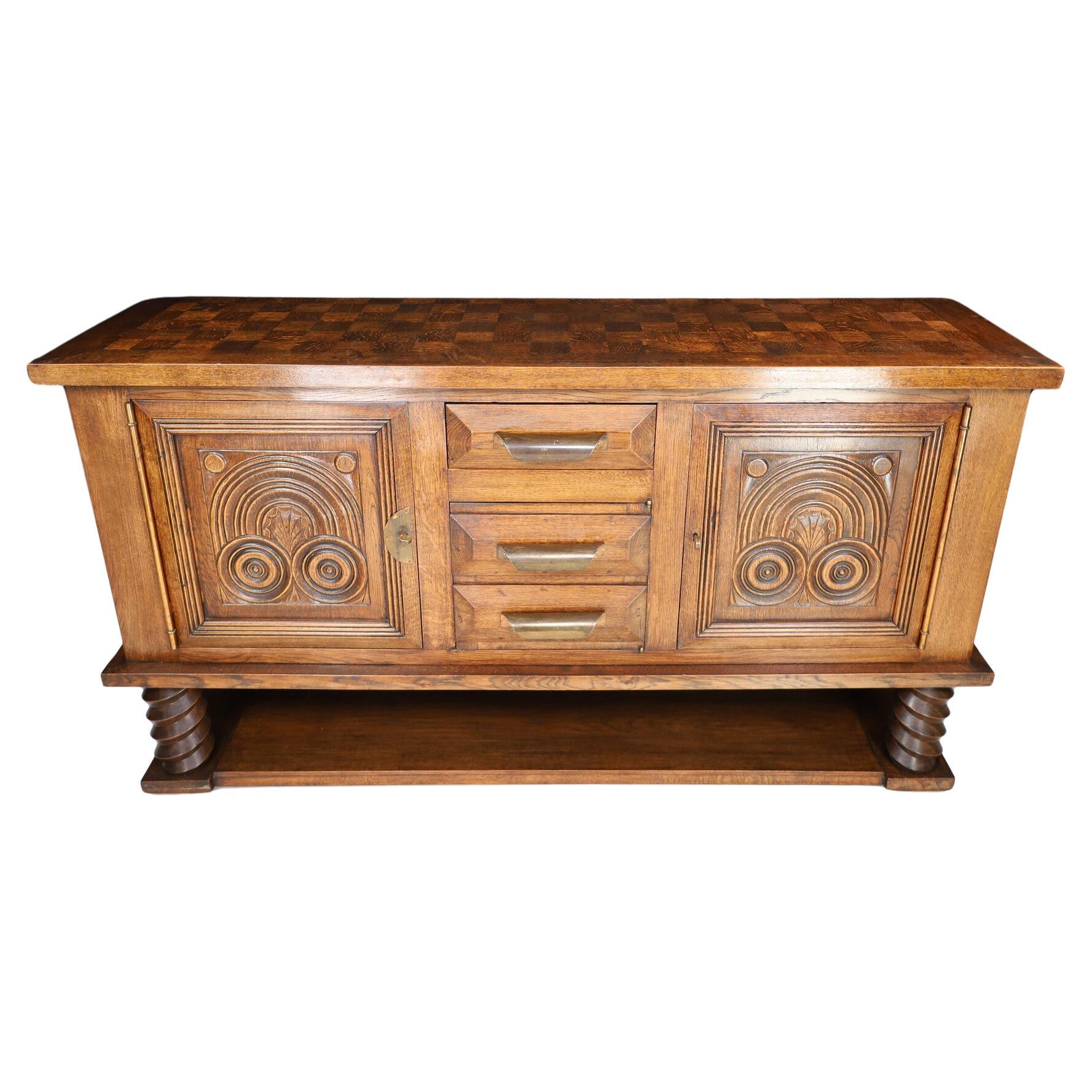 Here is a gorgeous oak Art Deco sideboard by Charles Dudouyt circa 1940s. The top is inlayed with stunning oak precise squares that comes together for a solid top that is a masterpiece. The open space below allows the true craftsmanship to shine