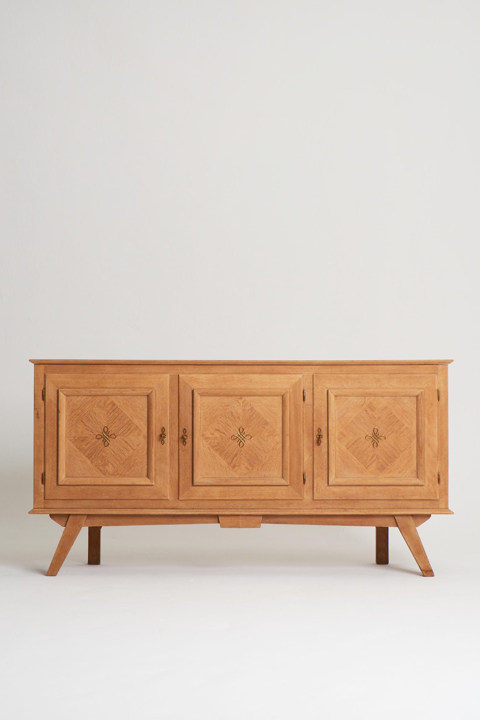 An Oak parquetry three-door sideboard, with brass accents.
France, Circa 1940.