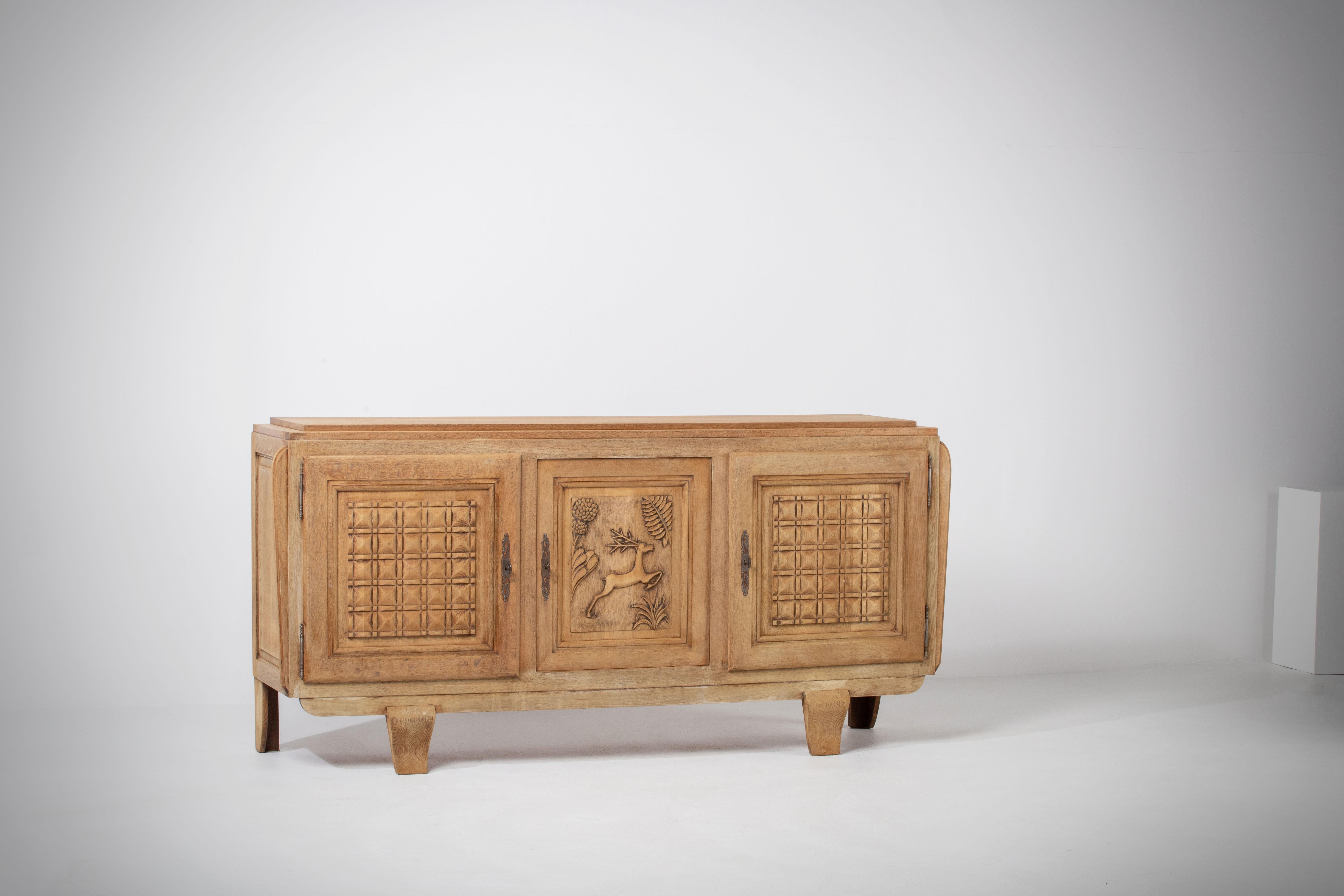 Credenza, solid oak, France, 1940s.
Large Art Deco Brutalist sideboard. 
The credenza consists of two storage facilities covered with very detailed designed door panels, in the center an handcarved hunting scene.
 

 