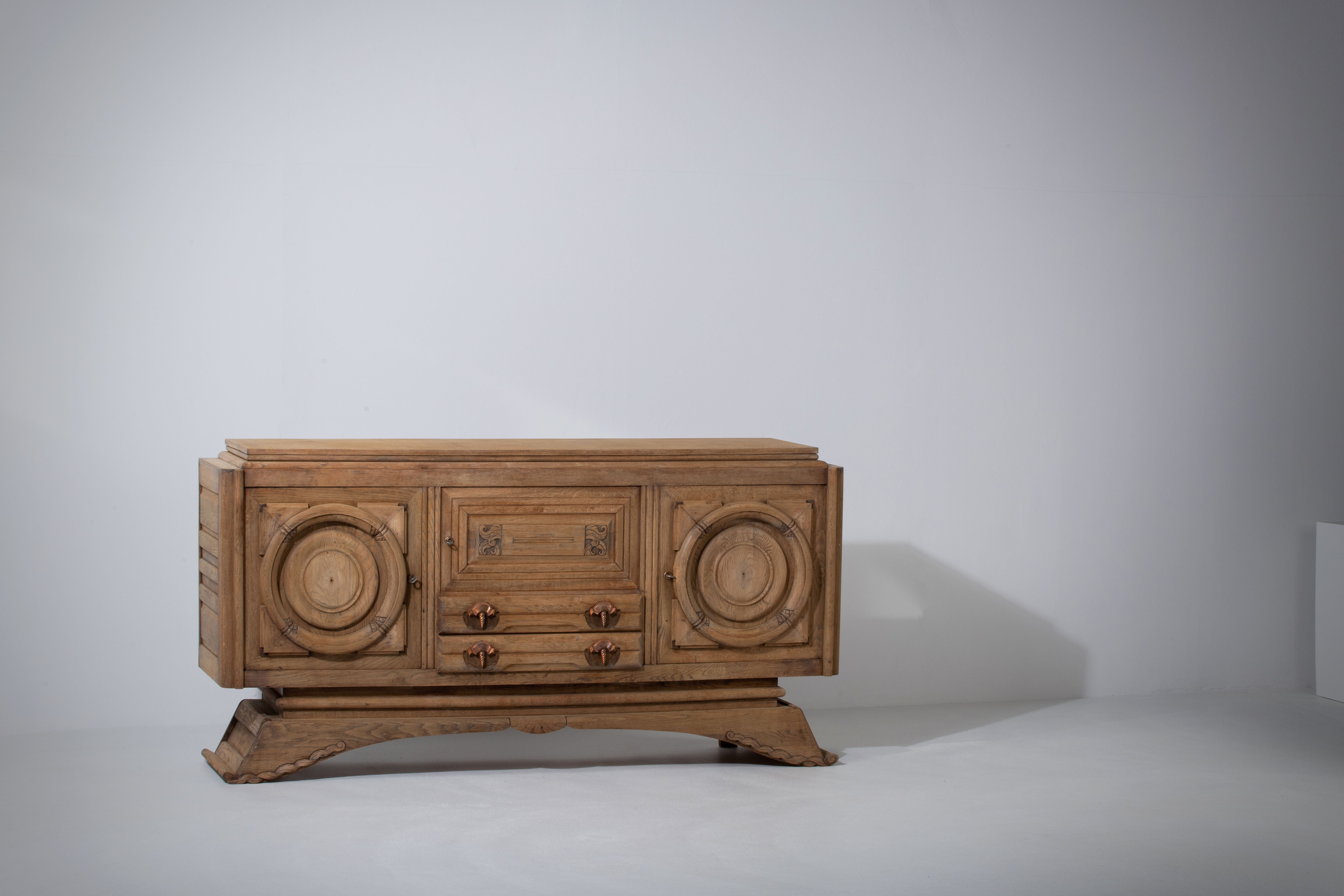 Credenza, solid oak, France, 1940s.
Large Art Deco Brutalist sideboard. 
The credenza consists of two storage facilities covered with very detailed designed door panels, in the center an hand carved hunting scene.
Shows signs of use and some