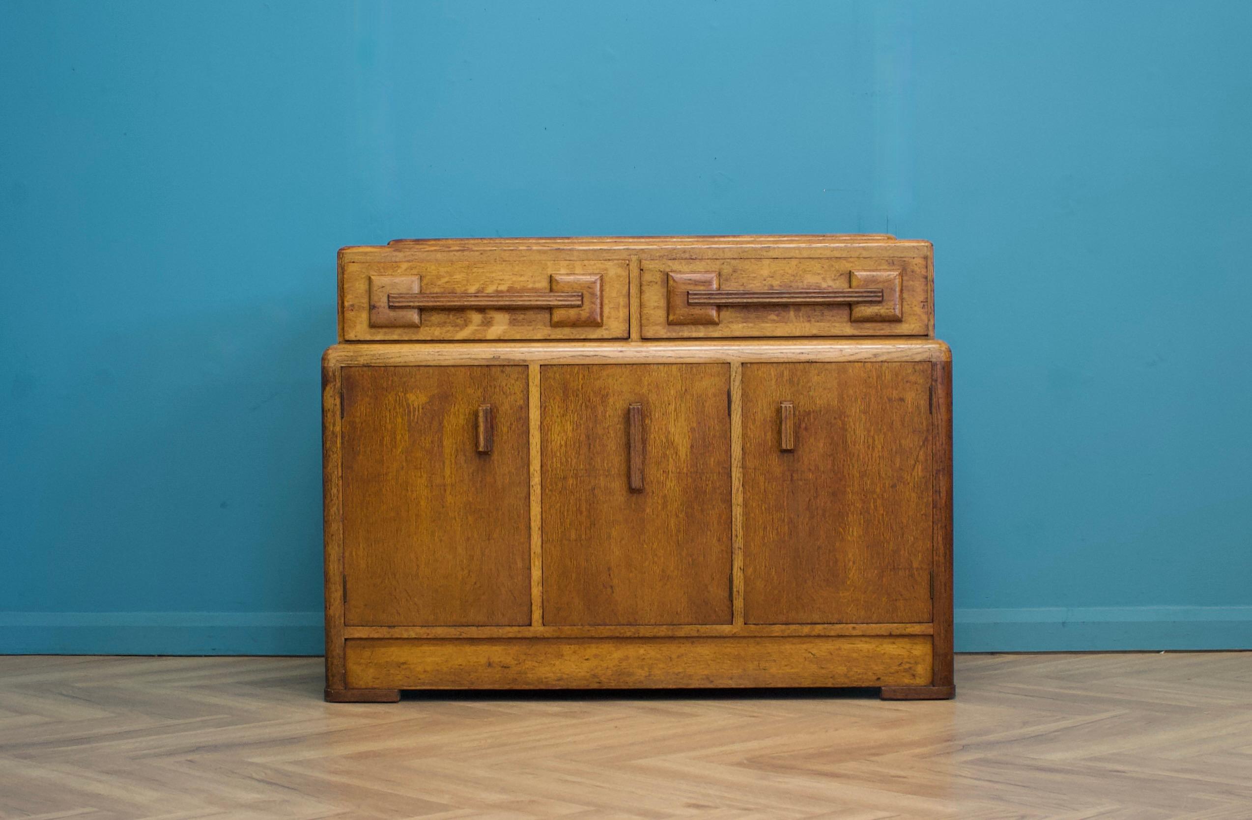 This high-quality oak Art Deco sideboard, circa 1930s.
Attributed to E Gomme ( G Plan) in the manner of Heals
Featuring two cupboards, each with a shelf, and two drawers.