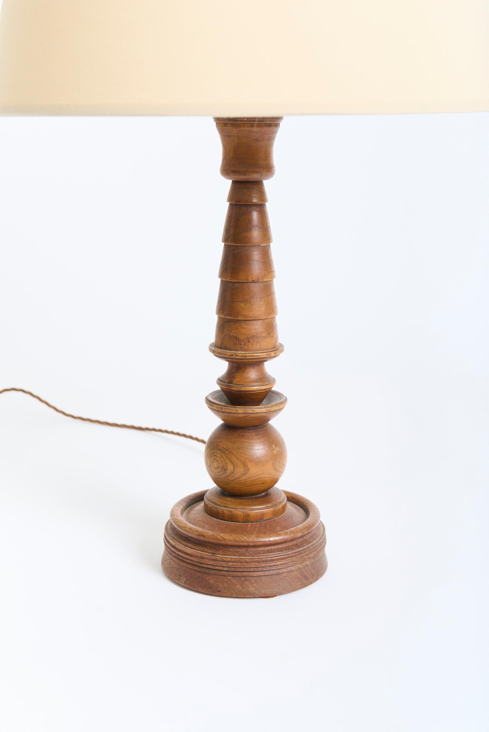 An Art Deco turned oak table lamp
France, Circa 1940
With the shade: 67 cm high by 41 cm diameter
Lamp base only: 46.5 cm high by 14.5 cm diameter