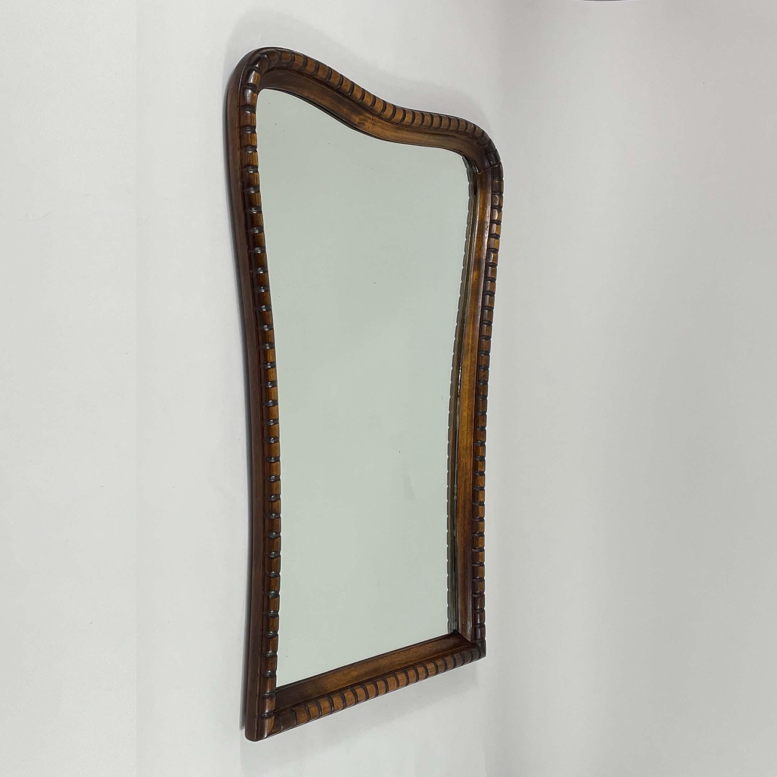 This large and heavy wall mirror was designed and manufactured in Italy in the 1940s. It features a hand carved stained oak frame and mirror glass.

Overall condition is very good, with a nice warm vintage patina to the frame and some wear to the