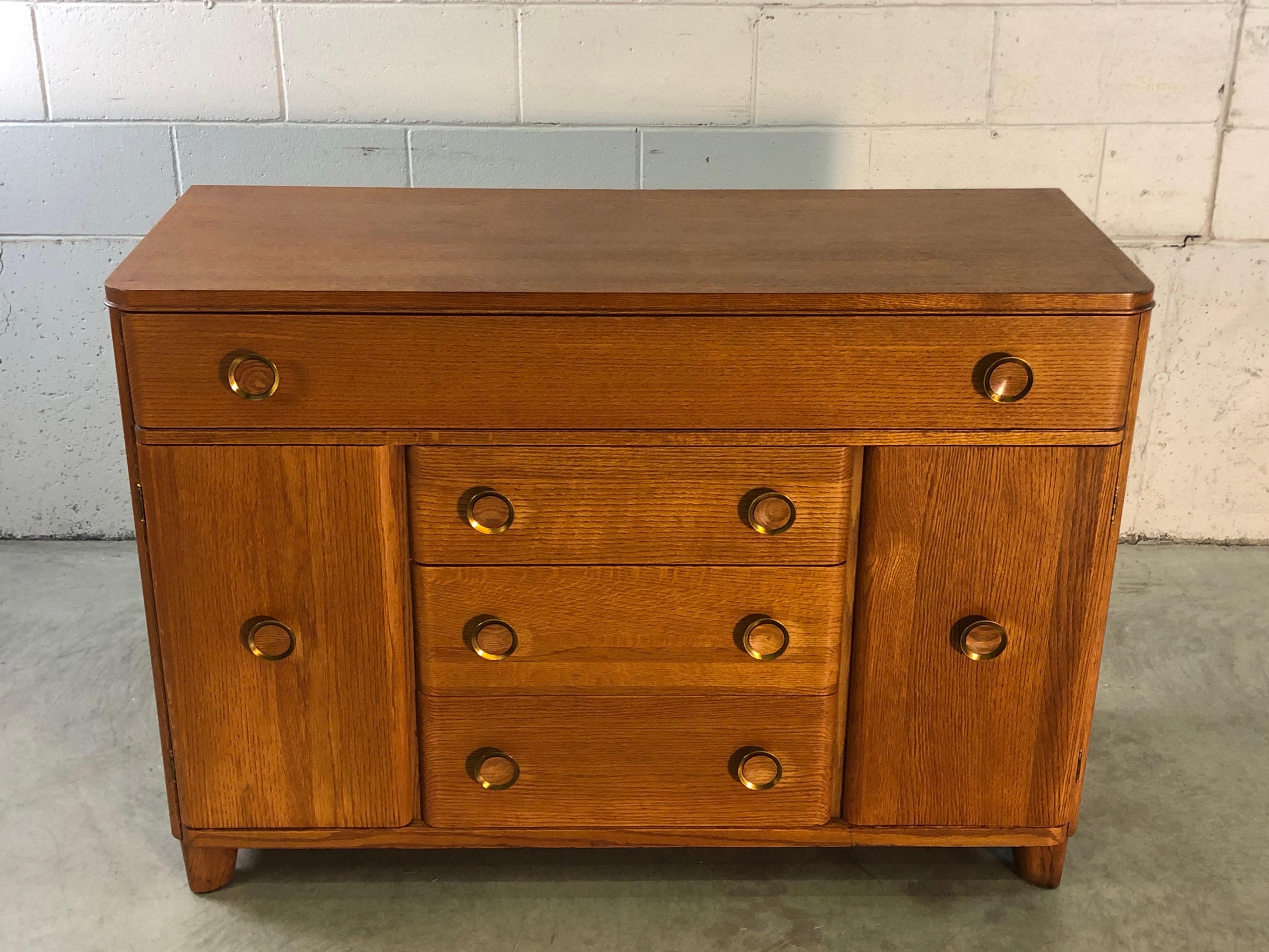 Art Deco oakwood buffet server with four drawers and side storage. The sides have shelves that are adjustable. The pulls are brass with an oak center. Marked inside the drawer. Newly refinished condition.