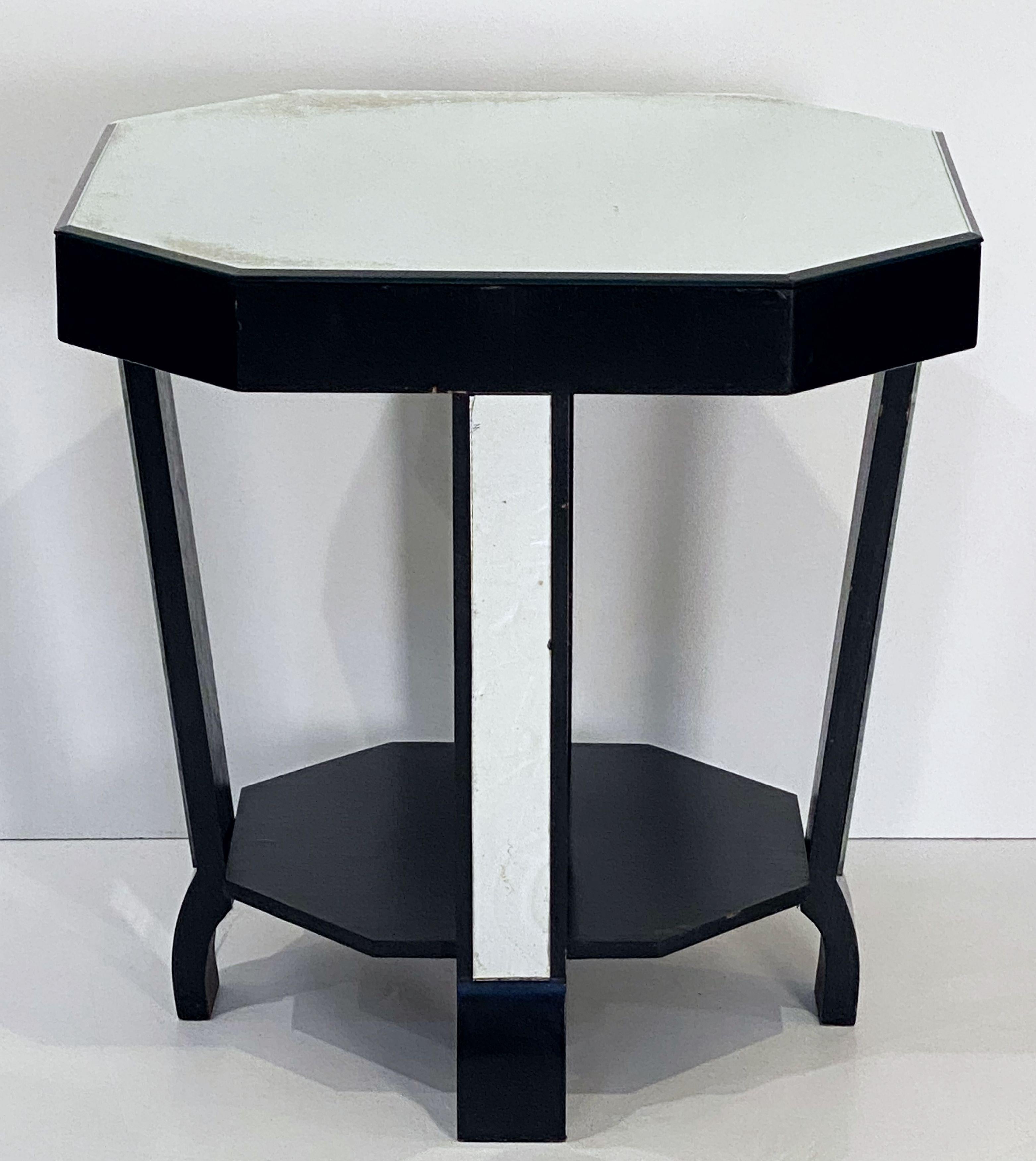 A fine English occasional or side table from the Art Deco era, featuring an octagonal mirrored glass top over a stylish ebonized four-legged frame with an eight-sided under-tier shelf and mirrored glass accents on the legs.

Note: Foxing to