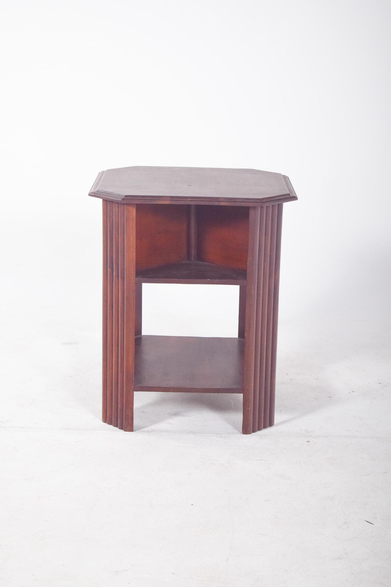 Octagonal side table. With two lower shelves, it is ideal as a functional and decorative element in various areas of the home. The structure has a robust and symmetrical design, with decorative fluted vertical columns at the corners. The warm-toned