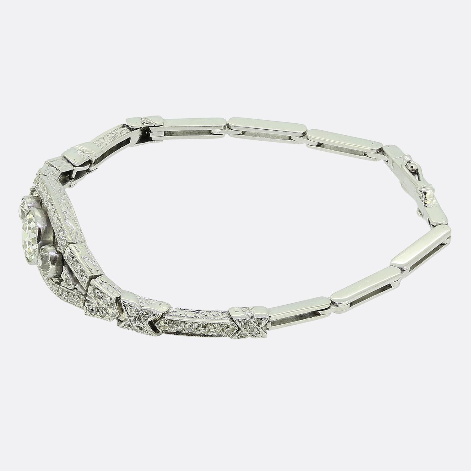 Aquí tenemos una fabulosa pulsera Art Déco elaborada en oro blanco de 14 ct. La pulsera presenta un impresionante diamante de talla europea antigua de 1,30 quilates en el centro de la cara, flanqueado a ambos lados por una piedra a juego ligeramente