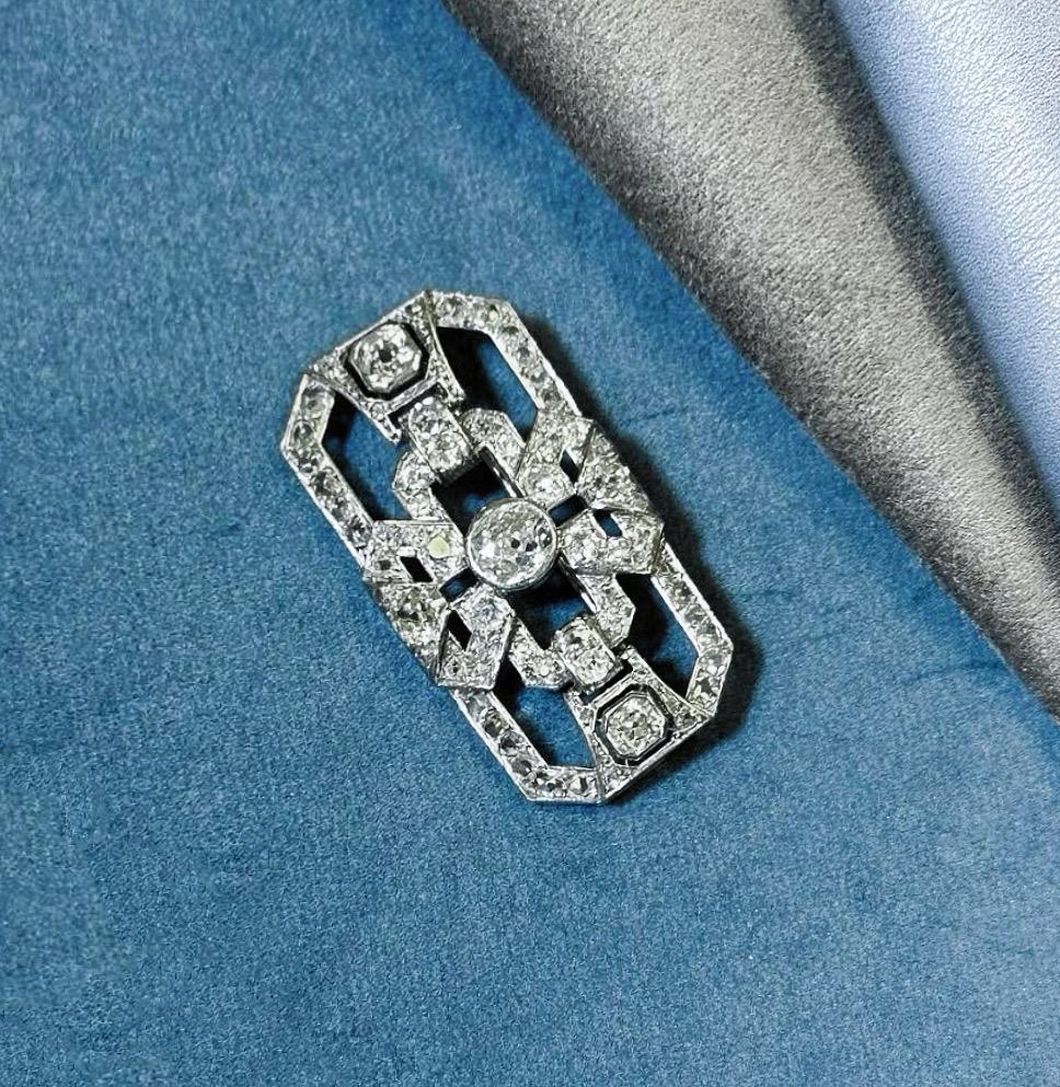 This stunning antique art deco old cut diamond brooch is set in 18k white gold with a total diamond weight of 3.5 carats.
 
Set in a symmetrical geometric design, a 1.3 carat old European cut diamond is in the centre, flanked by two 0.43 carat
