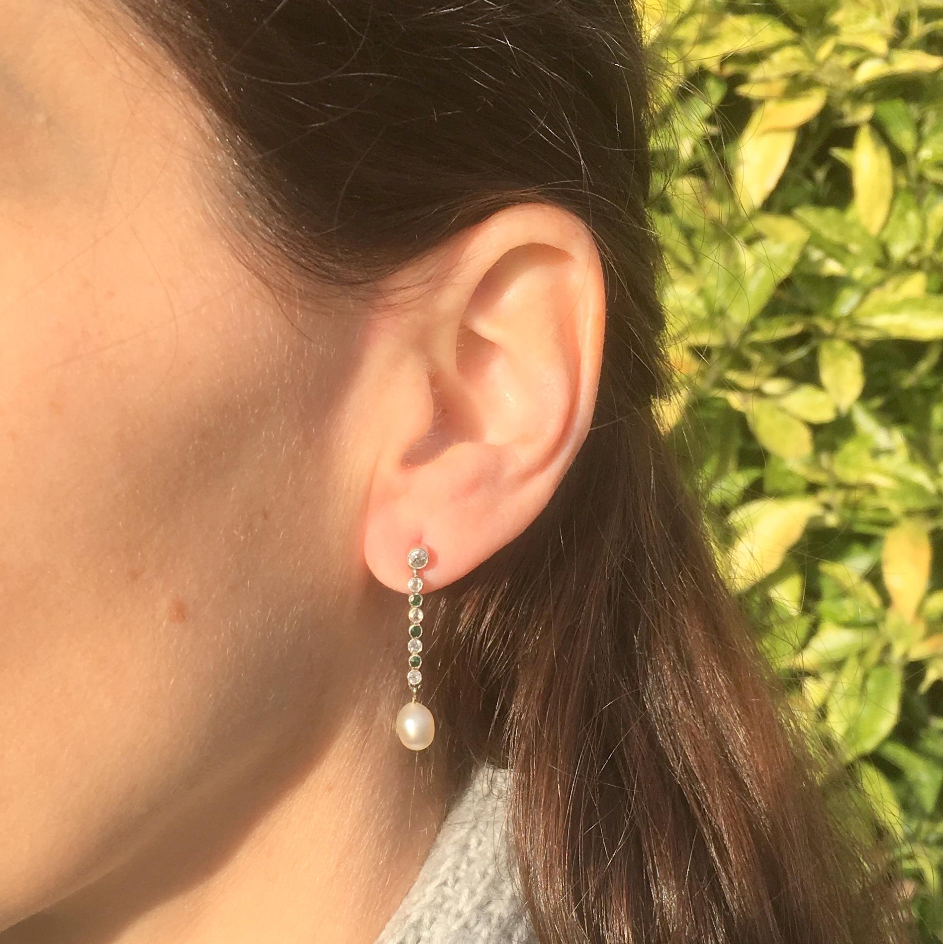 A delightful pair of old cut diamond, emerald and pearl drop earrings. Topping each earring is a rubover set diamond of approximately 0.12 carat. This connect to a lustrous cultured pearl via a linking bar set with old cut diamond and Colombian