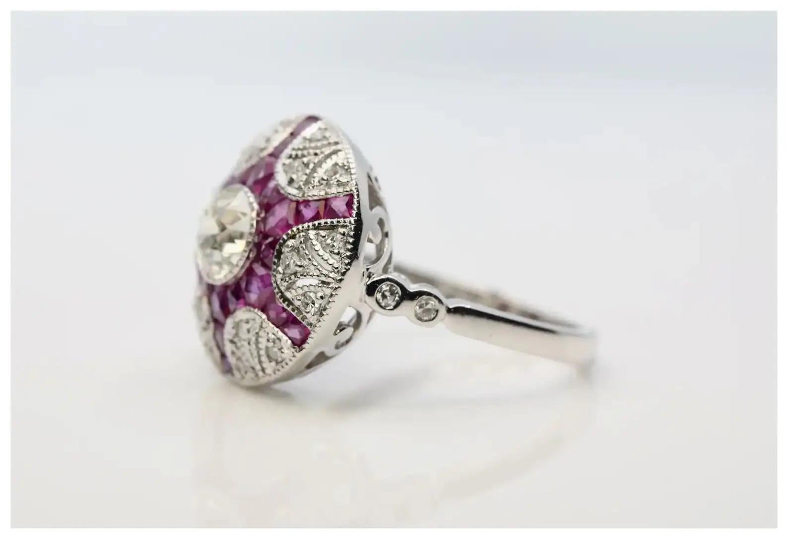 An Art Deco inspired diamond, and ruby dome style ring in platinum.

Centered by a 0.65 carat old European cut diamond of L color and VS2 clarity set in a miligrained platinum bezel.

Framed by rays of French cut rubies, and pave set diamonds.

The