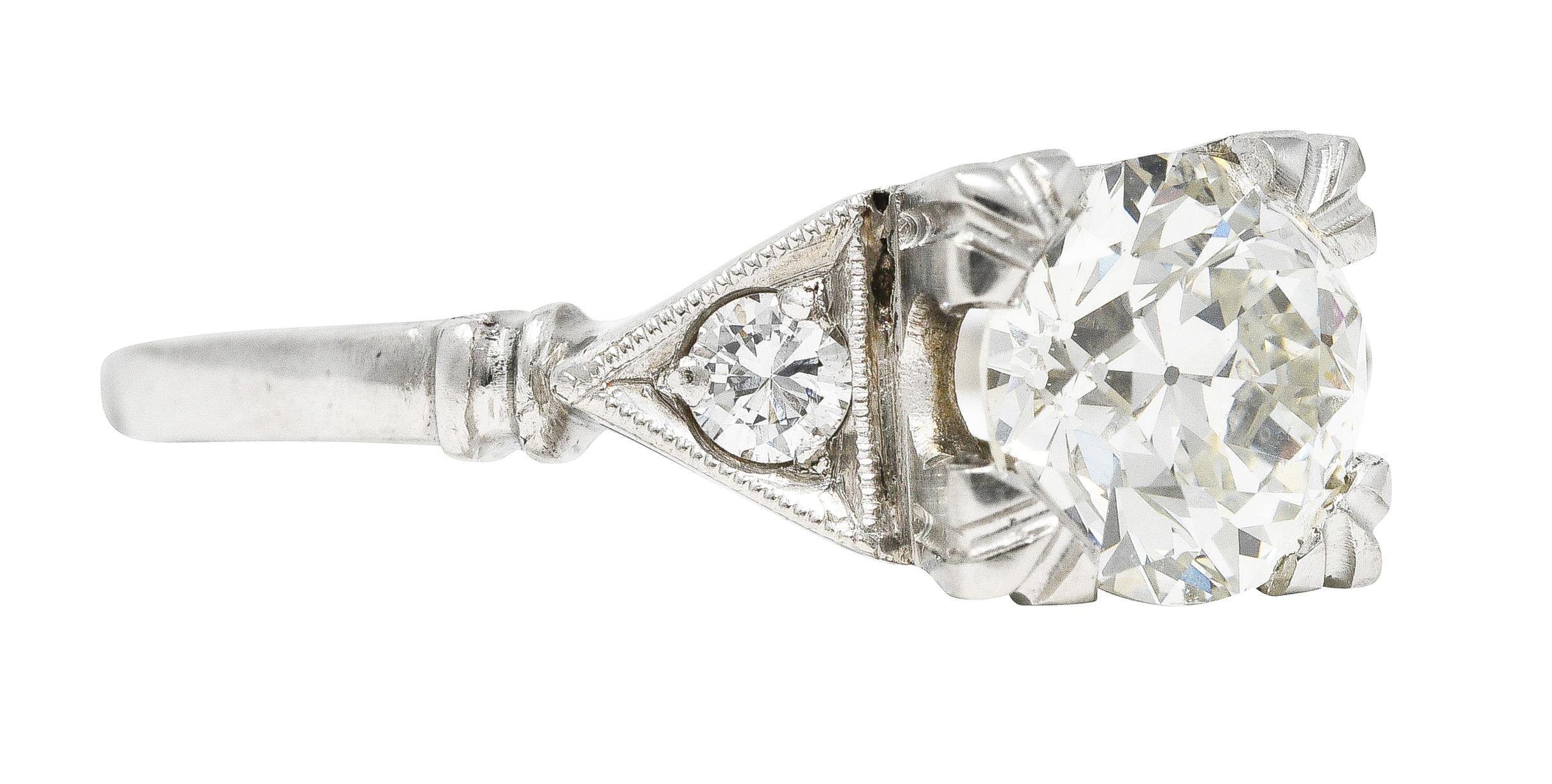 In der Mitte ein alter europäischer Diamant mit einem Gesamtgewicht von 1,14 Karat - Farbe K und Reinheit VVS1. In einem stilisierten Korb mit dreifach geteilten Zacken gefasst und von dreieckigen Kathedralschultern flankiert. Mit perlenbesetzten