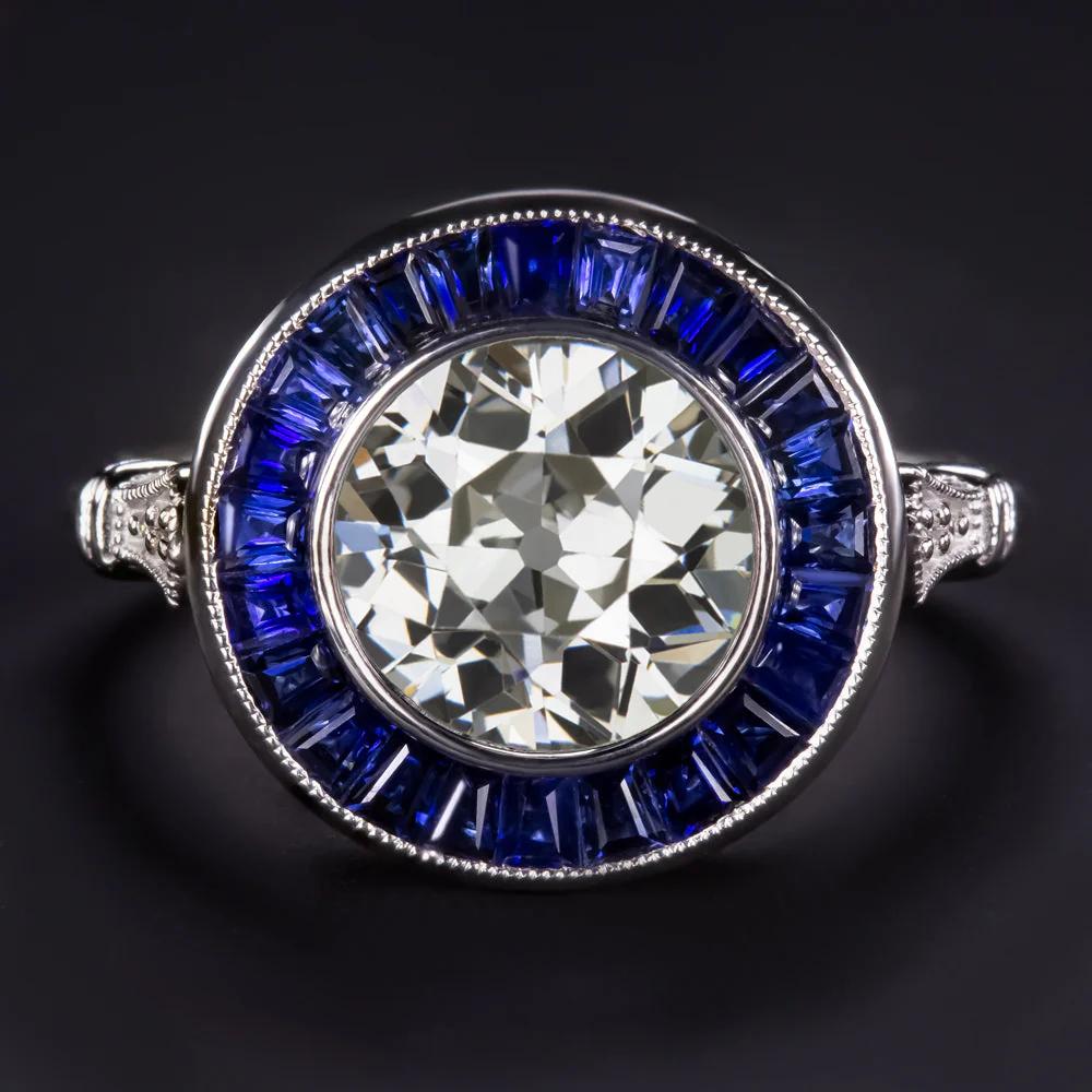 Cette exquise bague d'inspiration Art déco met en valeur un superbe diamant de 2,04 carats de taille Old European en son centre, entouré d'un halo vibrant de saphirs taillés sur mesure. Le diamant, certifié par EGL-USA, est une pierre vintage des