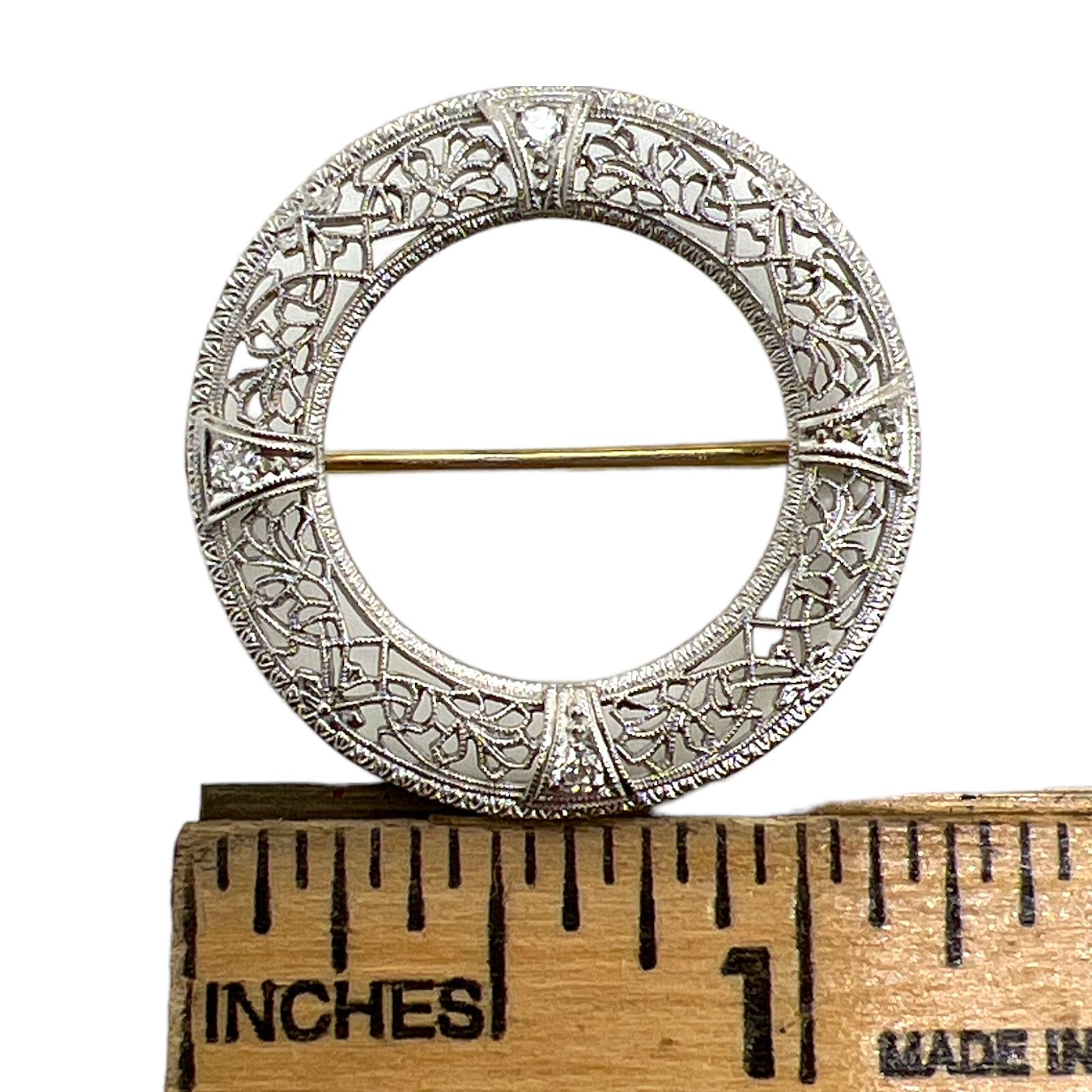 Art Deco filgree diamond vintage brooch fashioned in 14 karat yellow and white gold. The round brooch features 4 Old European cut diamonds weighing approximately .20 CTW and graded G-H color and SI clarity. The brooch is handcrafted with beautiful