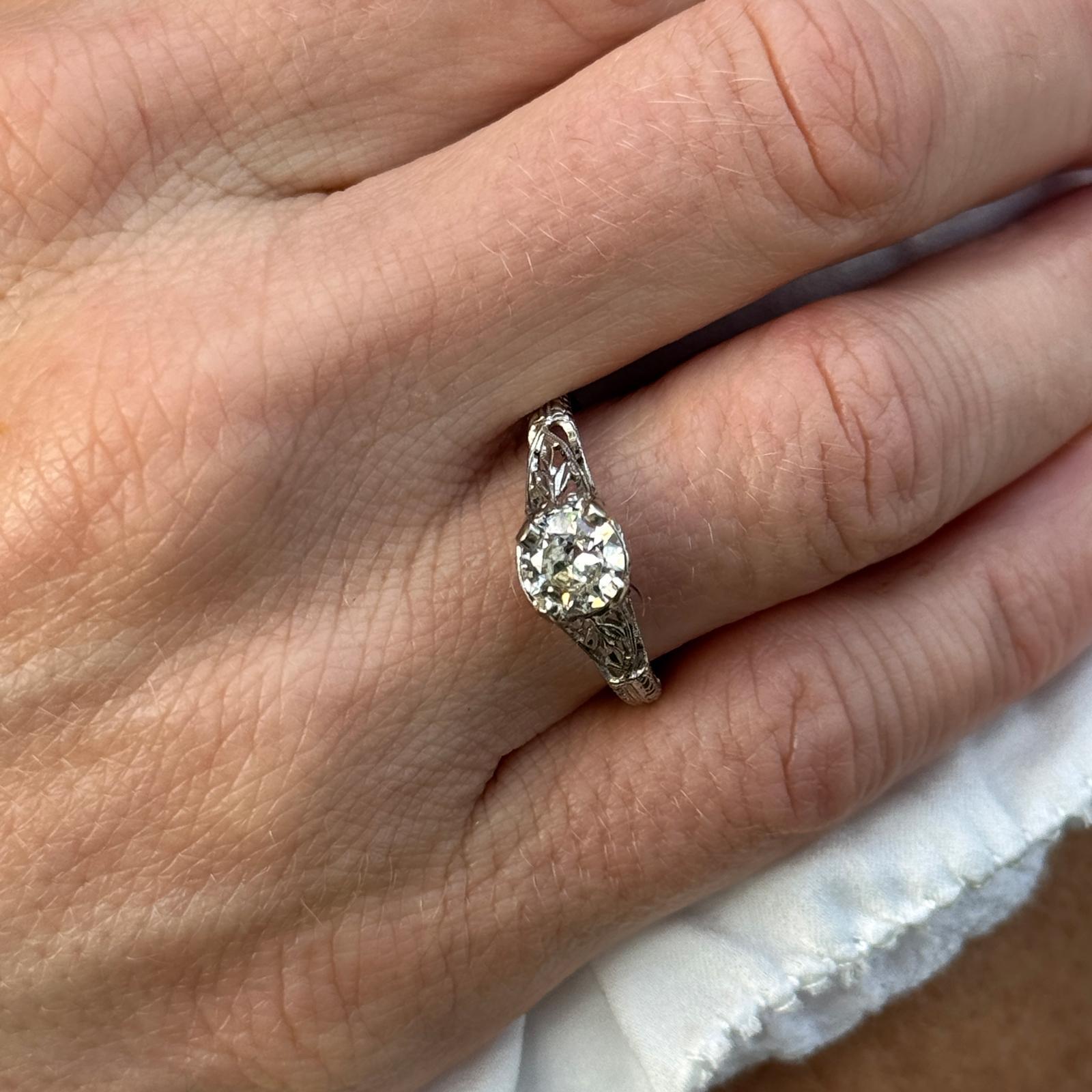 Original Art Deco diamond engagement ring handcrafted in 18 karat white gold. The ring features a .78 carat Old European cut diamond graded M color and VS clarity. The diamond is prong set in a filigree mounting measuring 7mm in width. The ring is